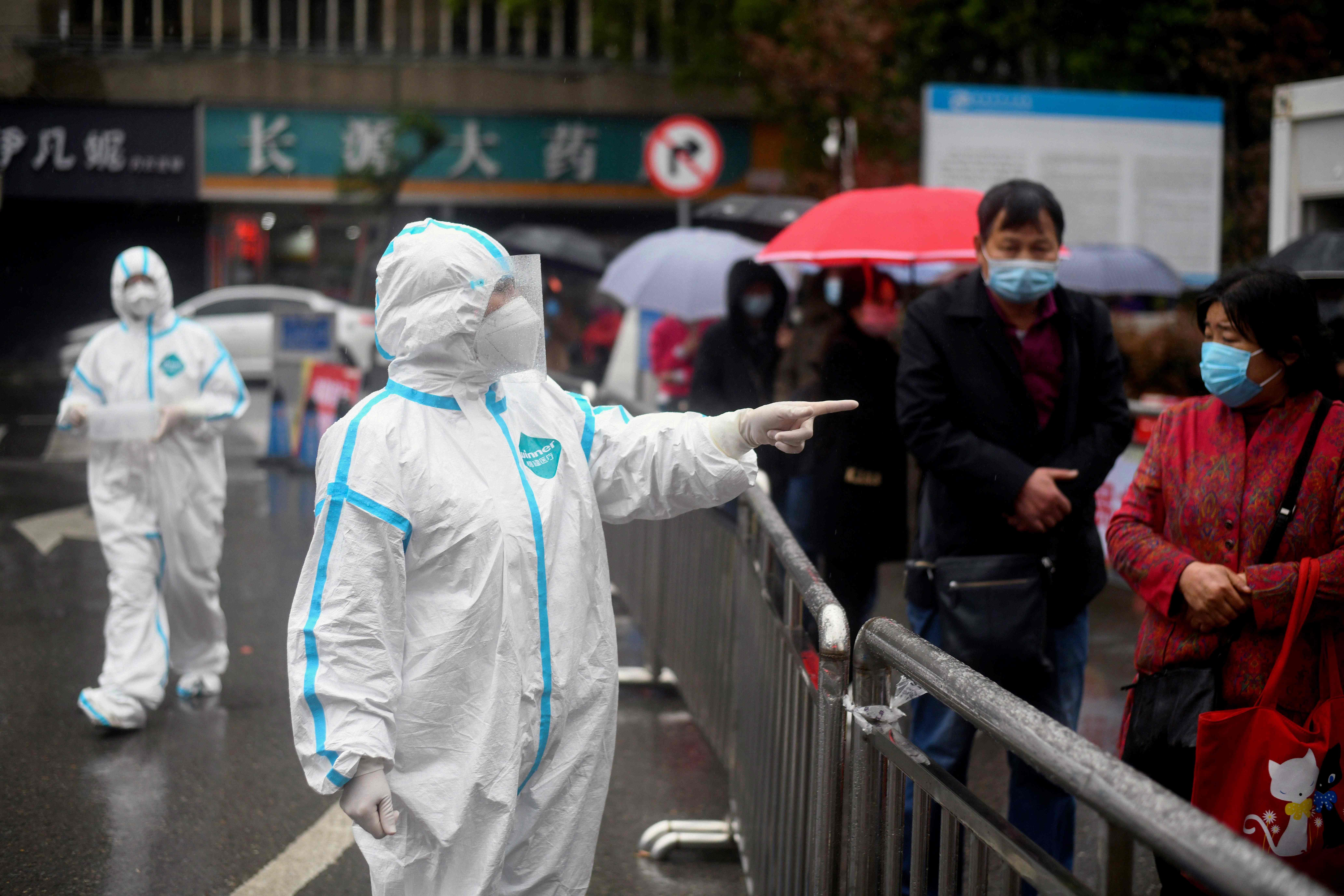 Pekerja medis mengawasi warga yang mengantre diperiksa di Rumah Sakit Huanggang Zhongxin, Tiongkok.
