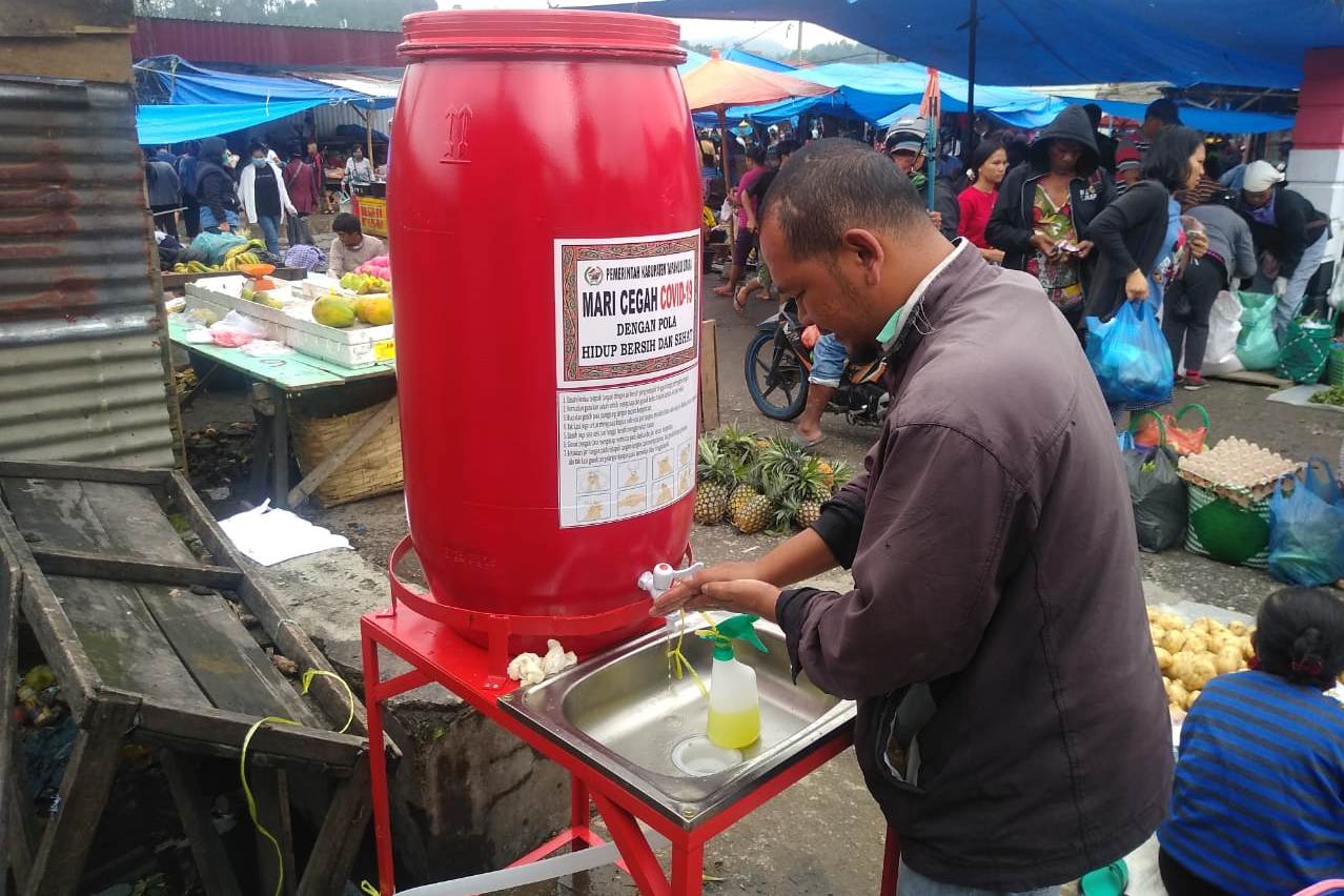 Henri Simanjuntak, 40, pengemudi becak motor di Pasar Tarutung sedang membersihkan tangan seusai bertransaksi.