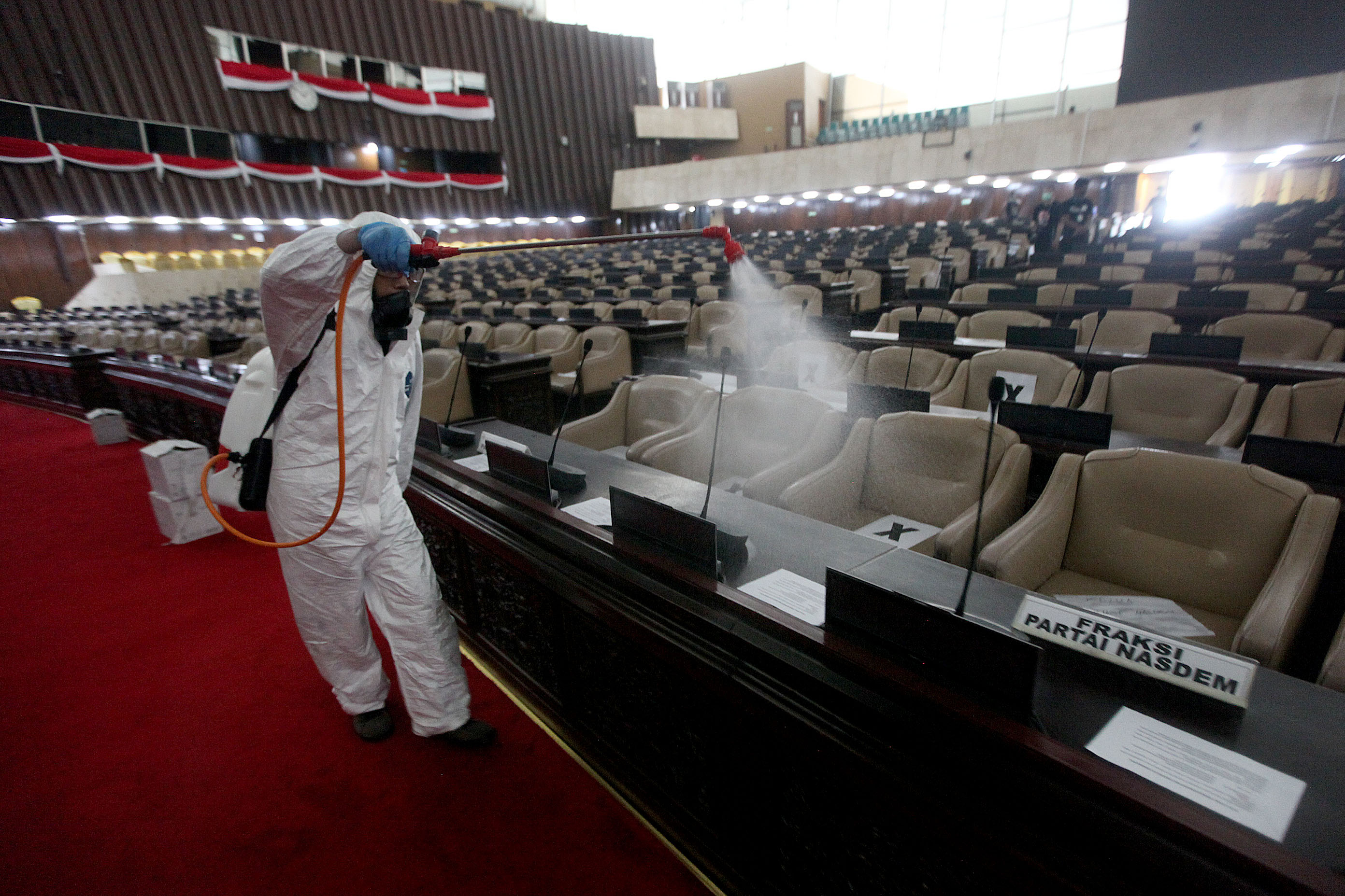 Petugas menyemprot disinfektan di ruangan Rapat Paripurna DPR RI, Minggu (29/3/2020)