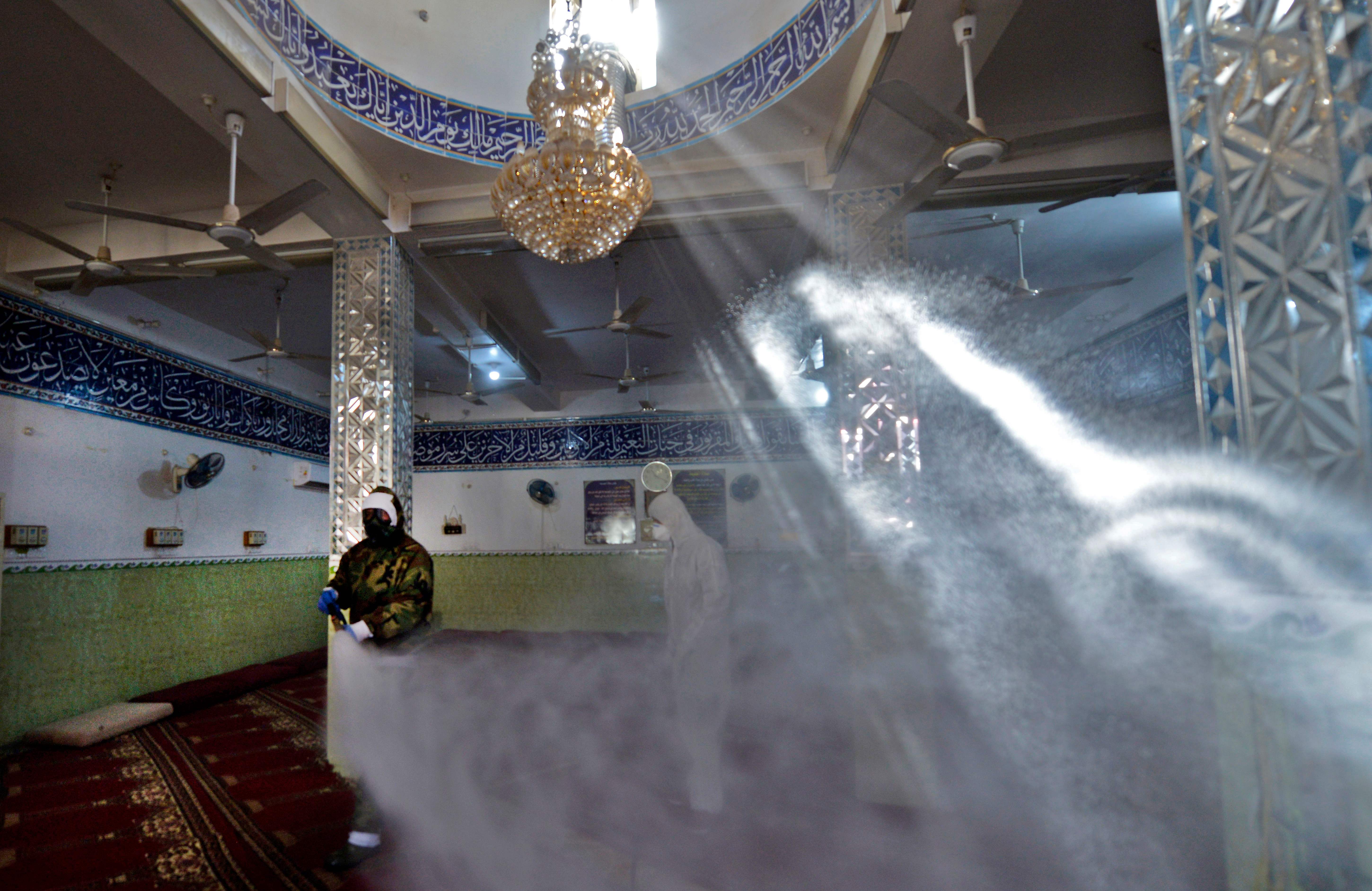 Seorang petugas menyemprotkan disinfektan di dalam sebuah masjid di Kota Najaf, Irak