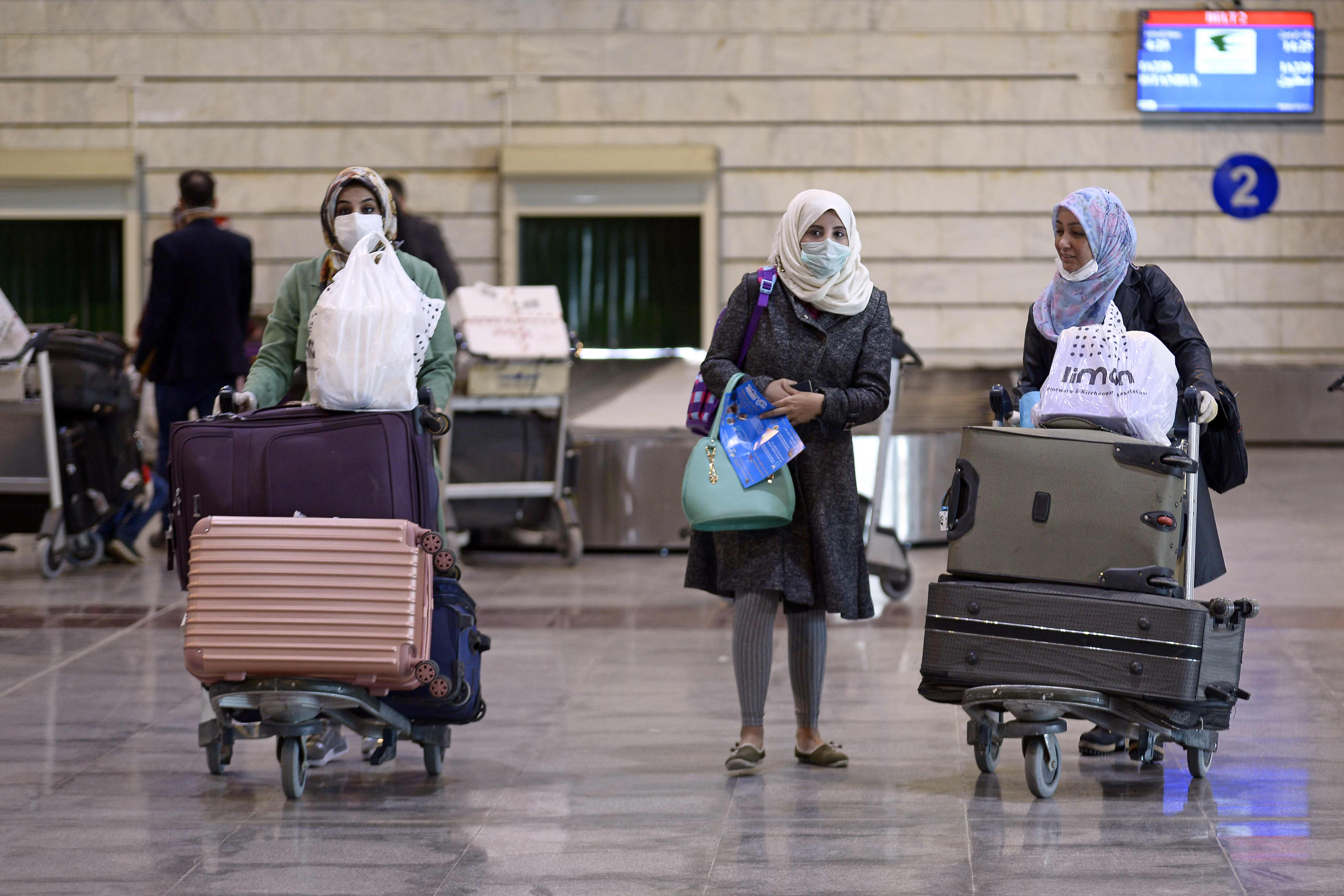 Warga Irak yang baru kembali dari Iran mengenakan masker di Bandara Najaf