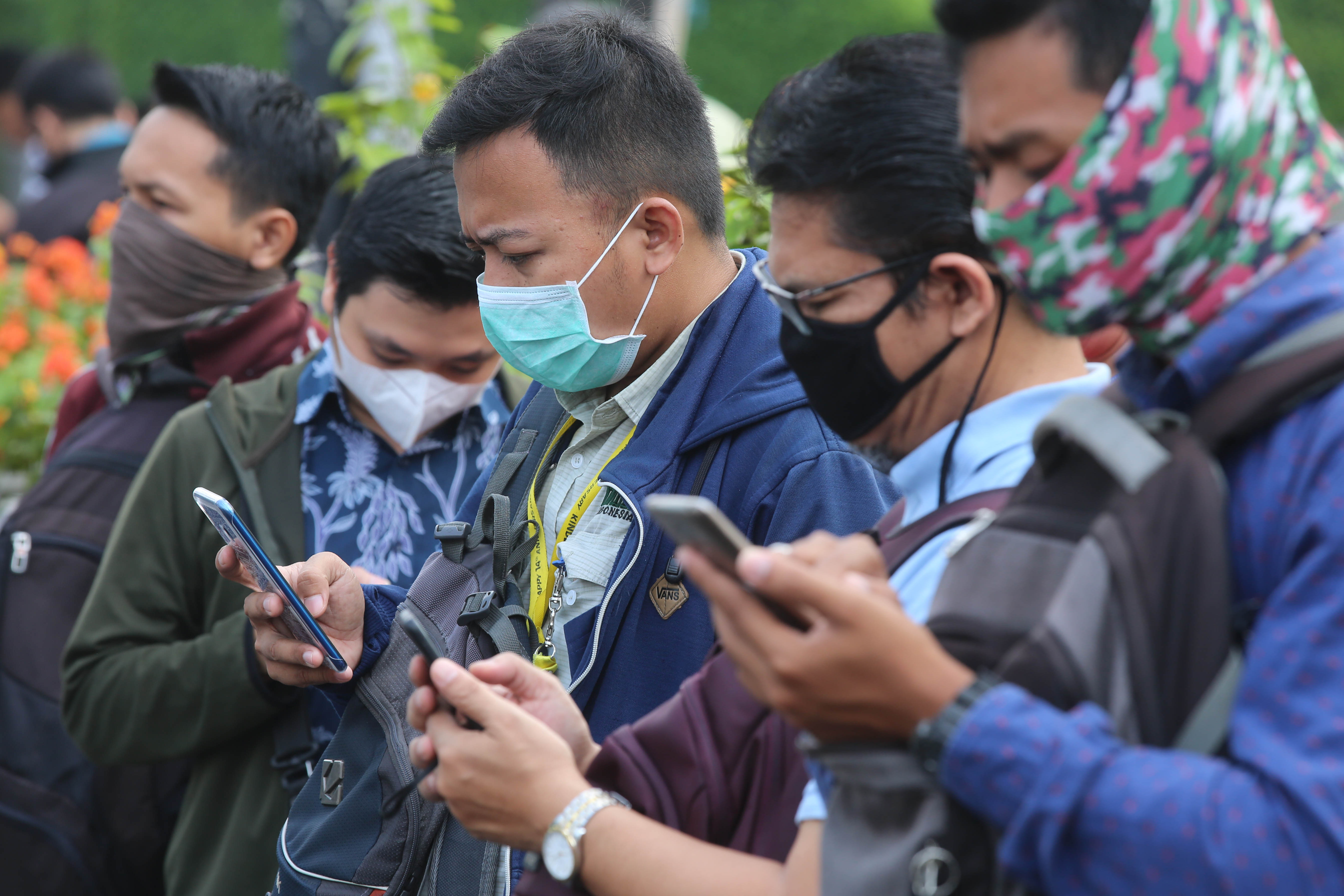 Pekerja menggunakan masker pelindung saat menunggu transportasi umum di kawasan Sudirman, Jakarta, untuk mengantisipasi wabah virus korona.