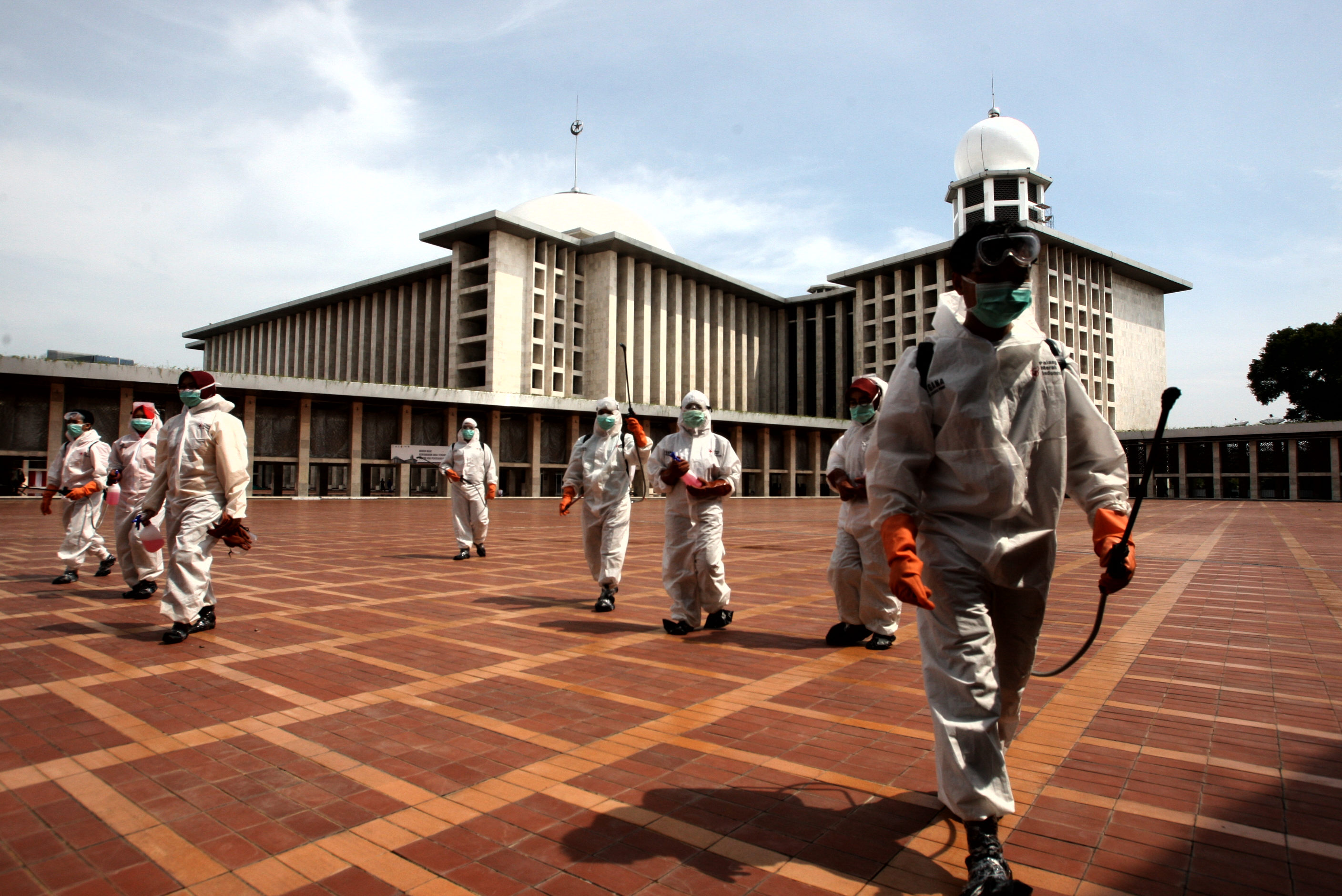 Petugas Palang Merah Indonesia (PMI) menyemprotkan disinfektan di area masjid Istiqlal, Jakarta, hari ini.