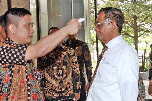 Petugas memeriksa suhu tubuh Menko Polhukam Mahfud MD saat menyambangi Kemenkum dan HAM, di Jakarta, kemarin.