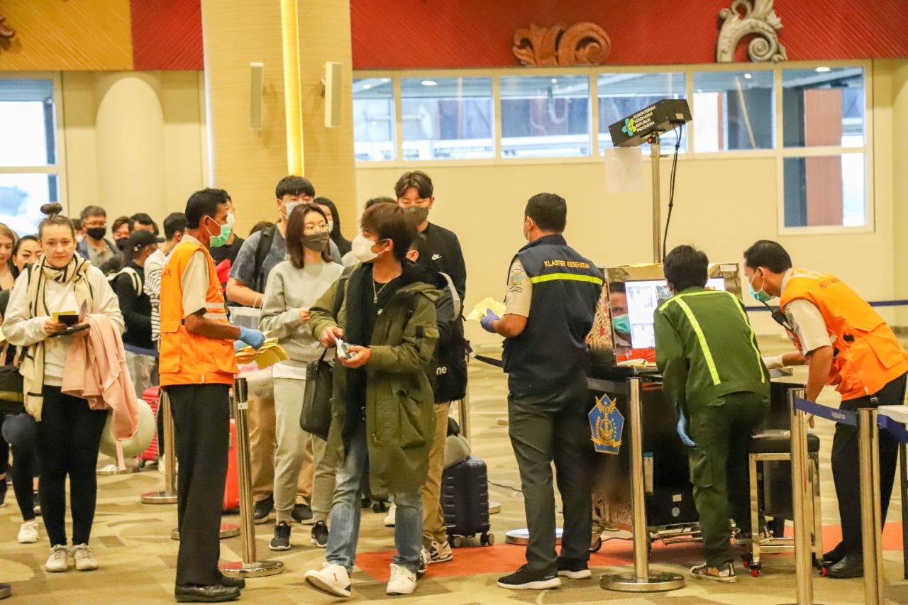 Para penumpang dari Kprea Selatan melewati jalur khusus terminal kedatangan di Bandara Ngurah Rai, dengan pemeriksaan ketat petugas bandara.
