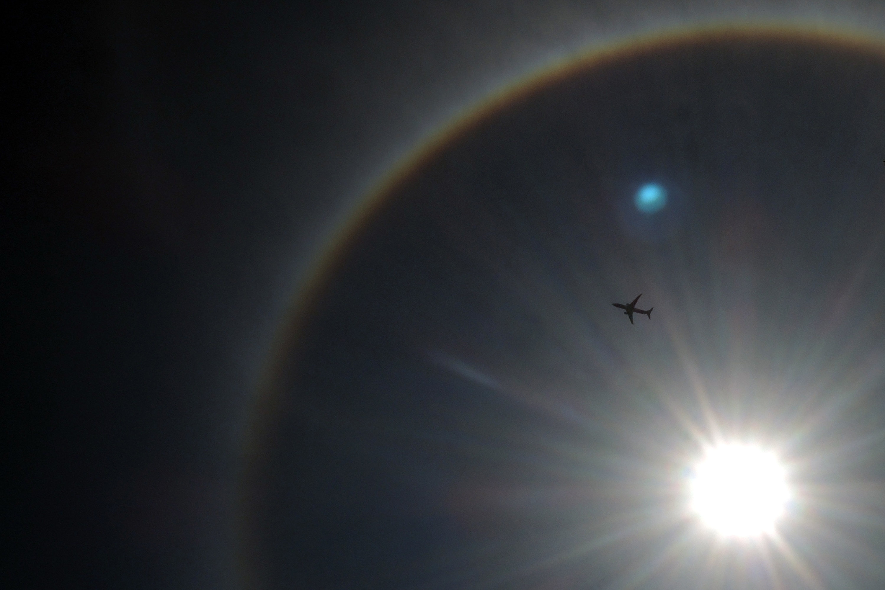 Pesawat melintasi langit di bawah terik matahari.