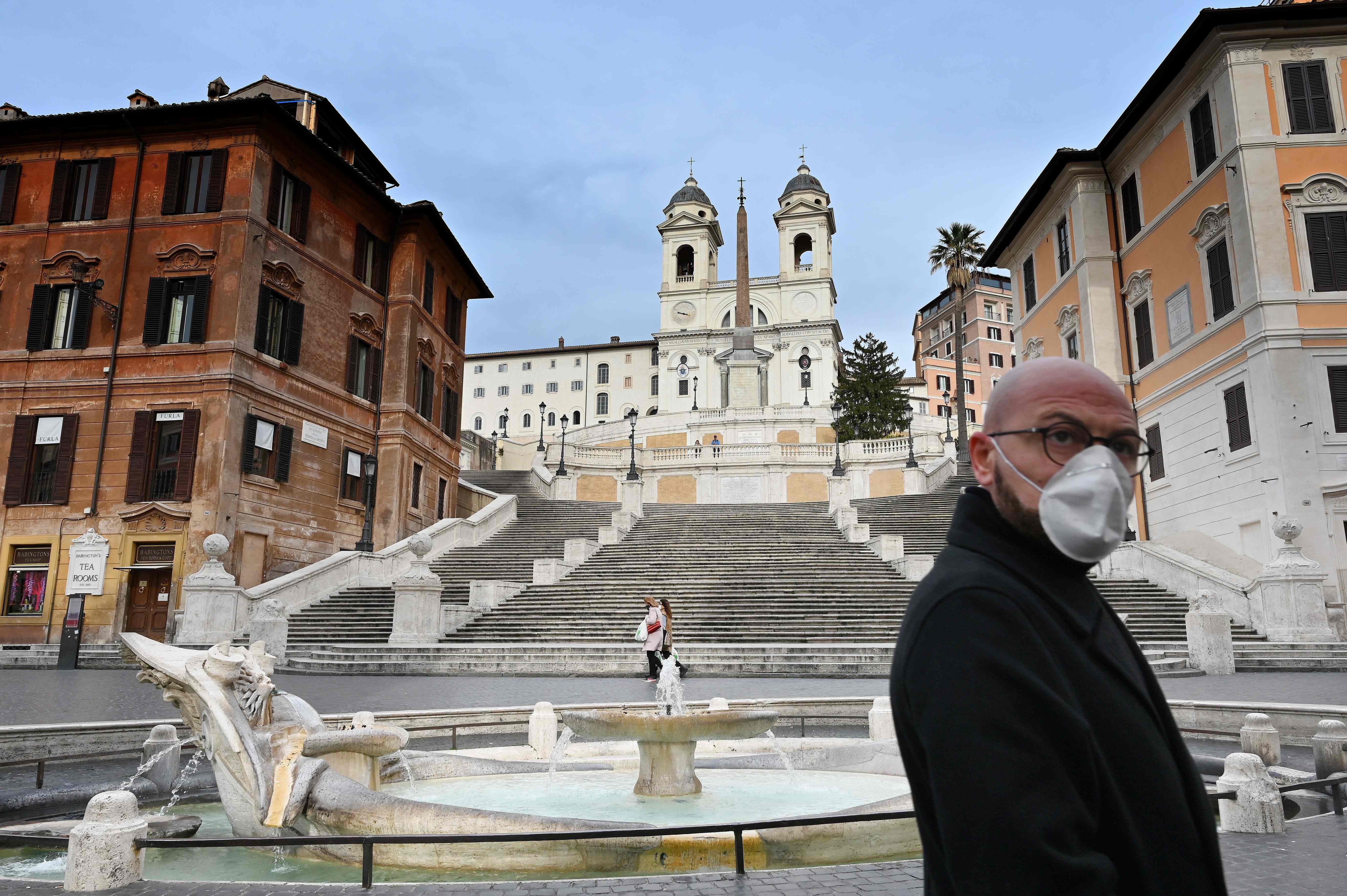Seorang warga memakai masker di di depan Spanish Steps, Piazza di Spagna, Roma, pusat wisata yang kini sepi, Kamis (12/3/2020).