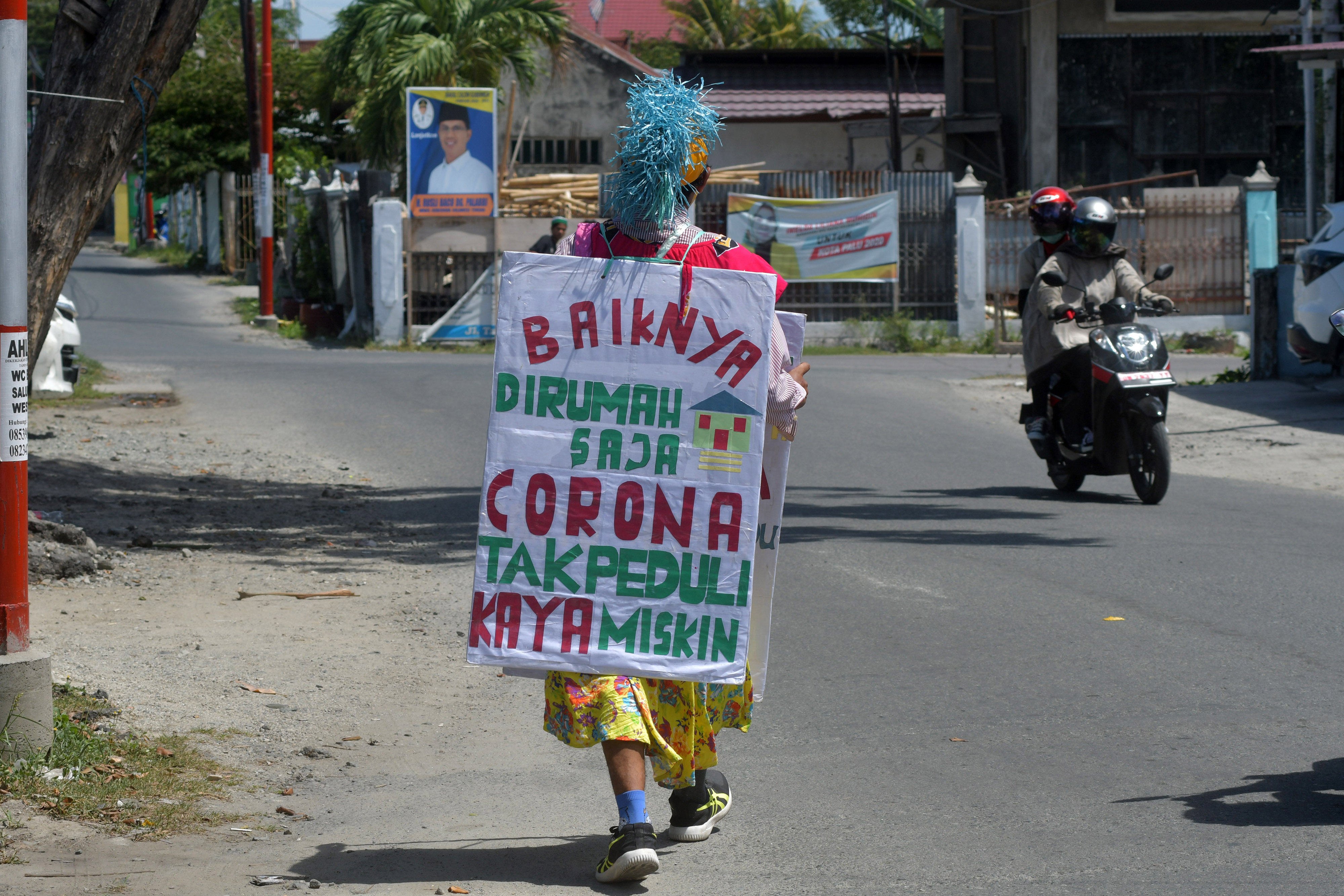 Seorang pria berkeliling mengenakan topeng dan membawa sejumlah imbauan guna mengajak masyarakat membantu penanganan Covid-19 di Palu.