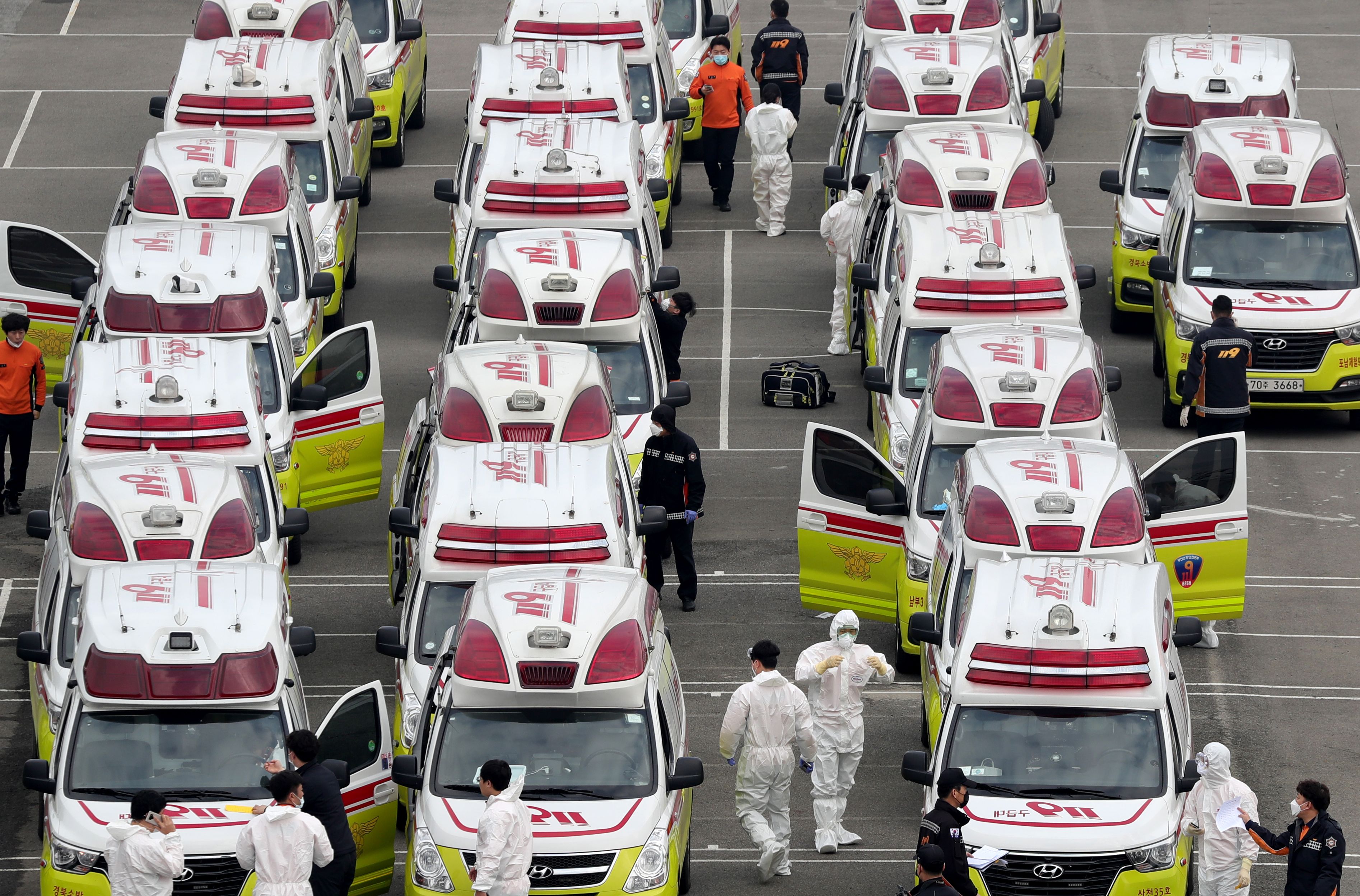 Paramedis berpakaian pelindung dan masker bersiap naik ambulans untuk mengevakuasi pasien positif virus korona