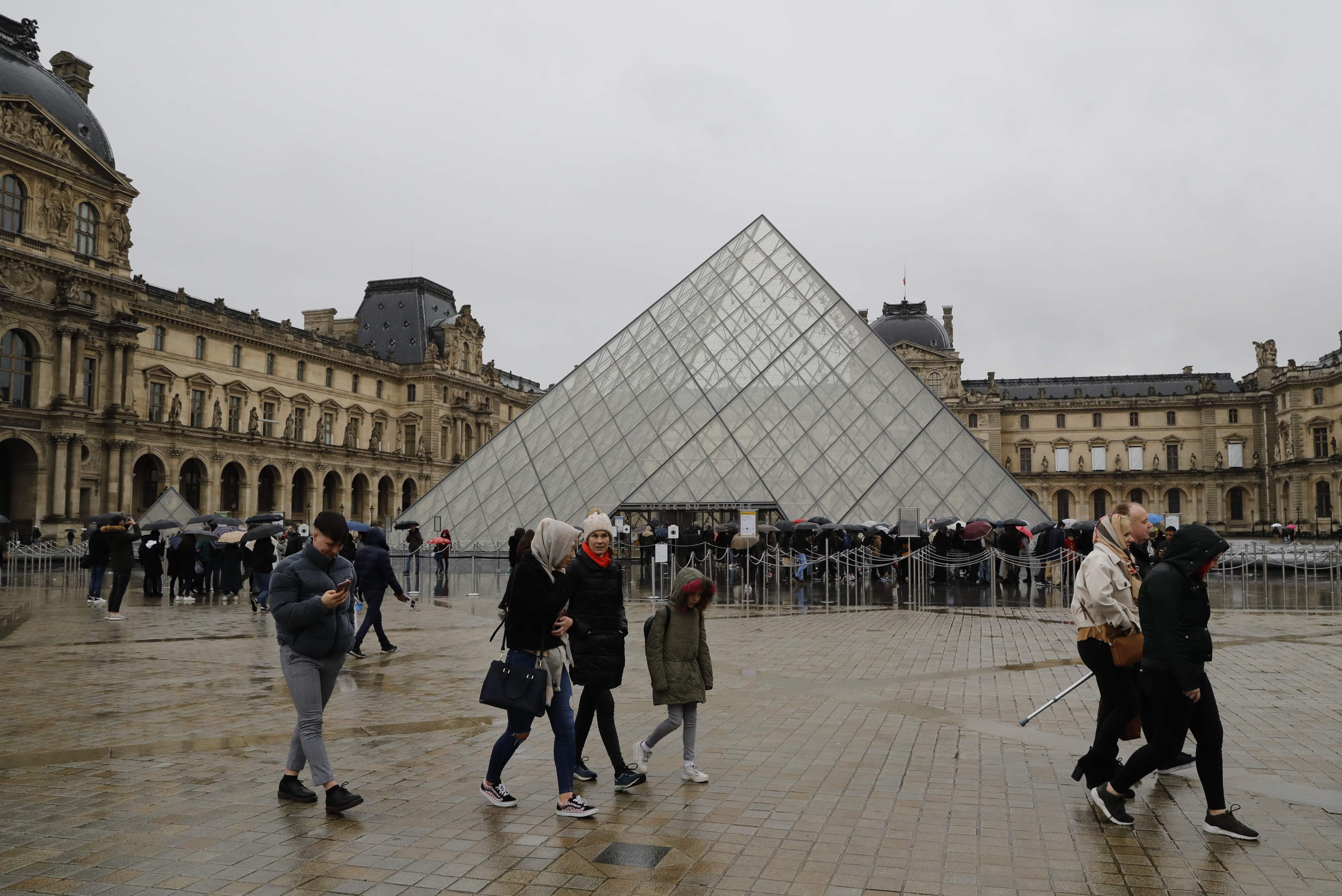 Sejumlah orang berjalan di depan Museum Louvre, Paris, Prancis.