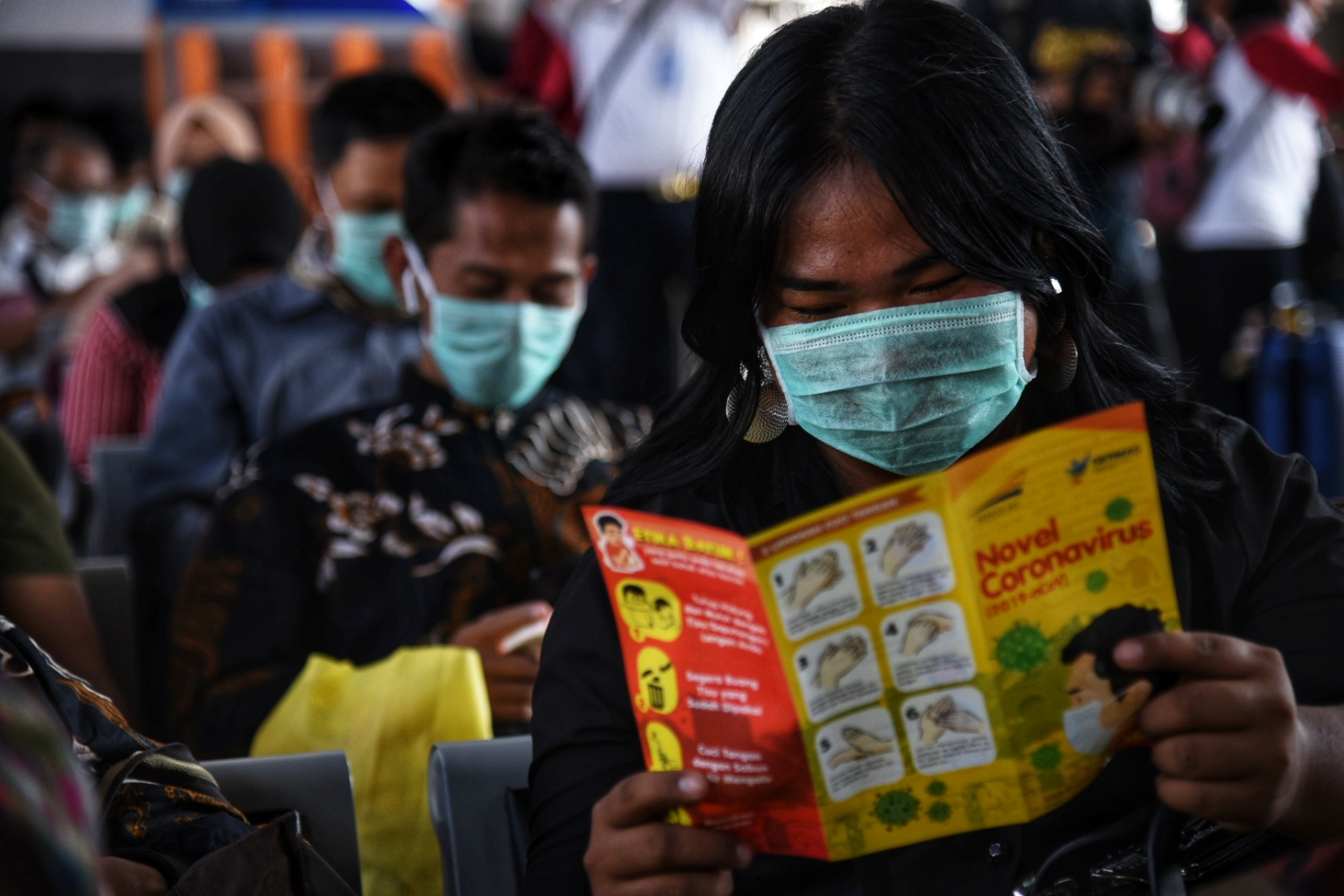 Calon penumpang kereta serius membaca pamflet terkait informasi virus korona yang dibagikan di Stasiun Pasar Senen.