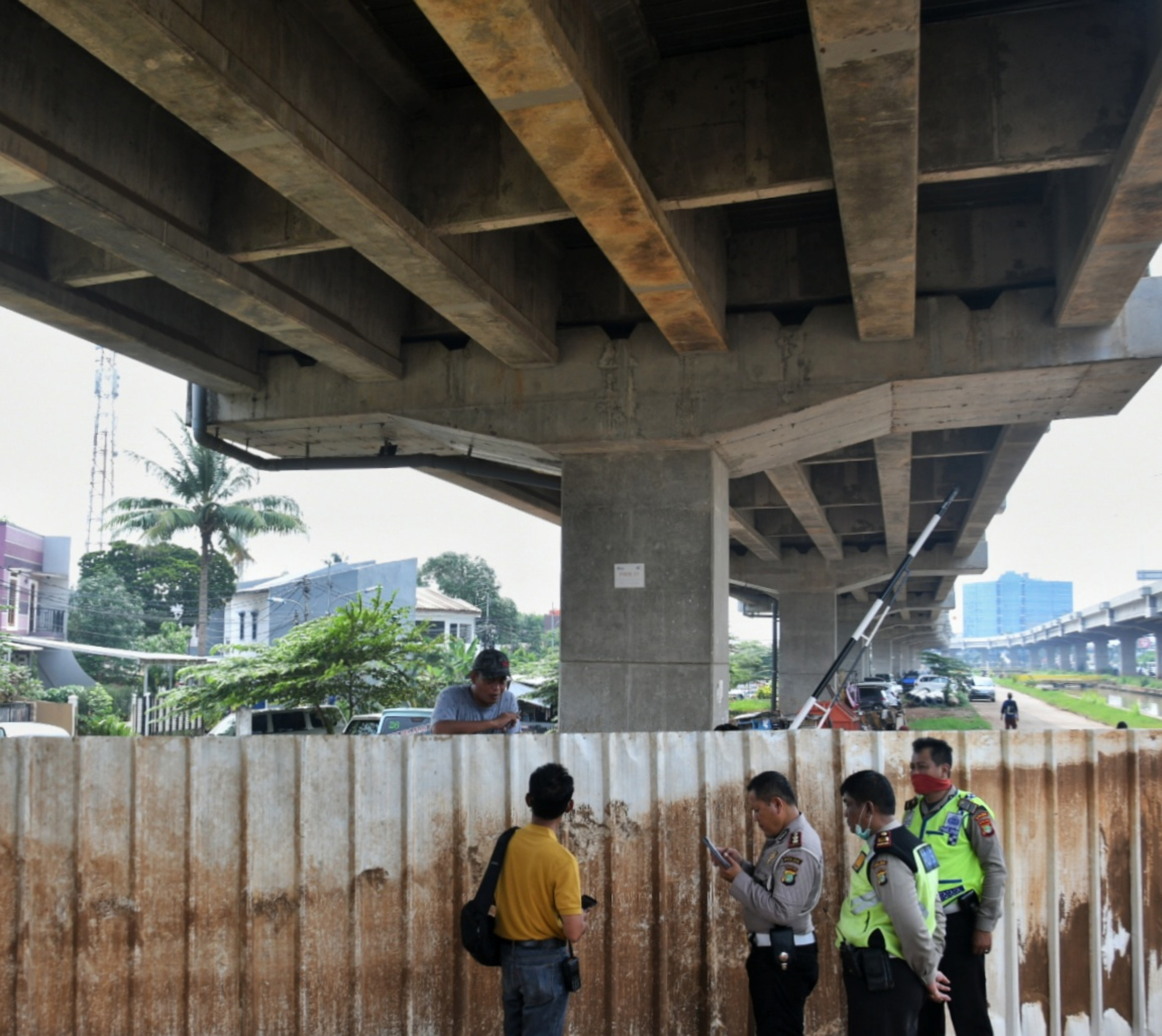 Polisi berbincang dengan warga di jalan yang ditutup seng dan besi di kawasan RW 04, Kelurahan Cipinang Melayu, Jakarta, Minggu (29/3).