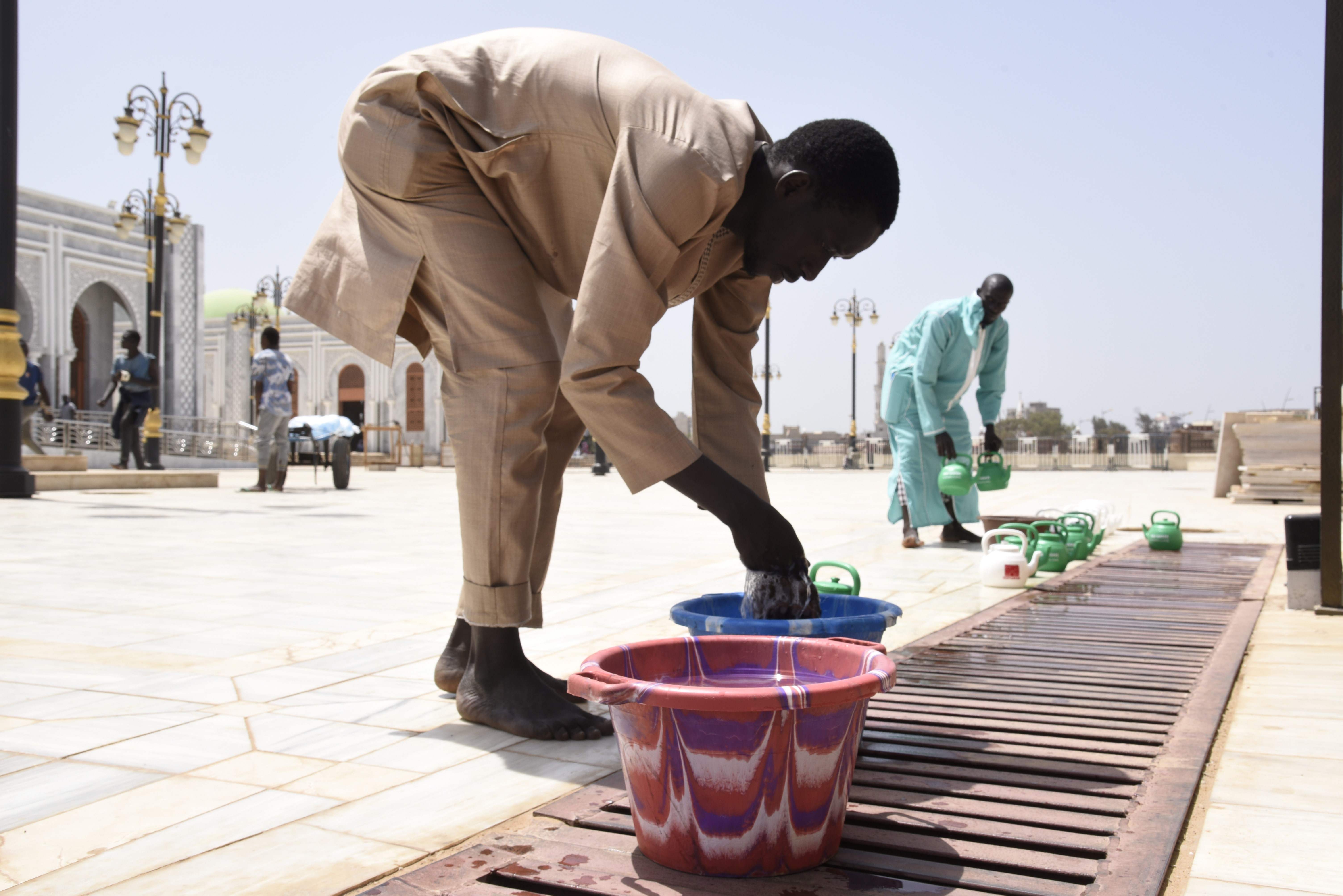 Seorang pria mencuci tangannya di depan Masjid Massalikul Jinaan, Dakar, Senegal