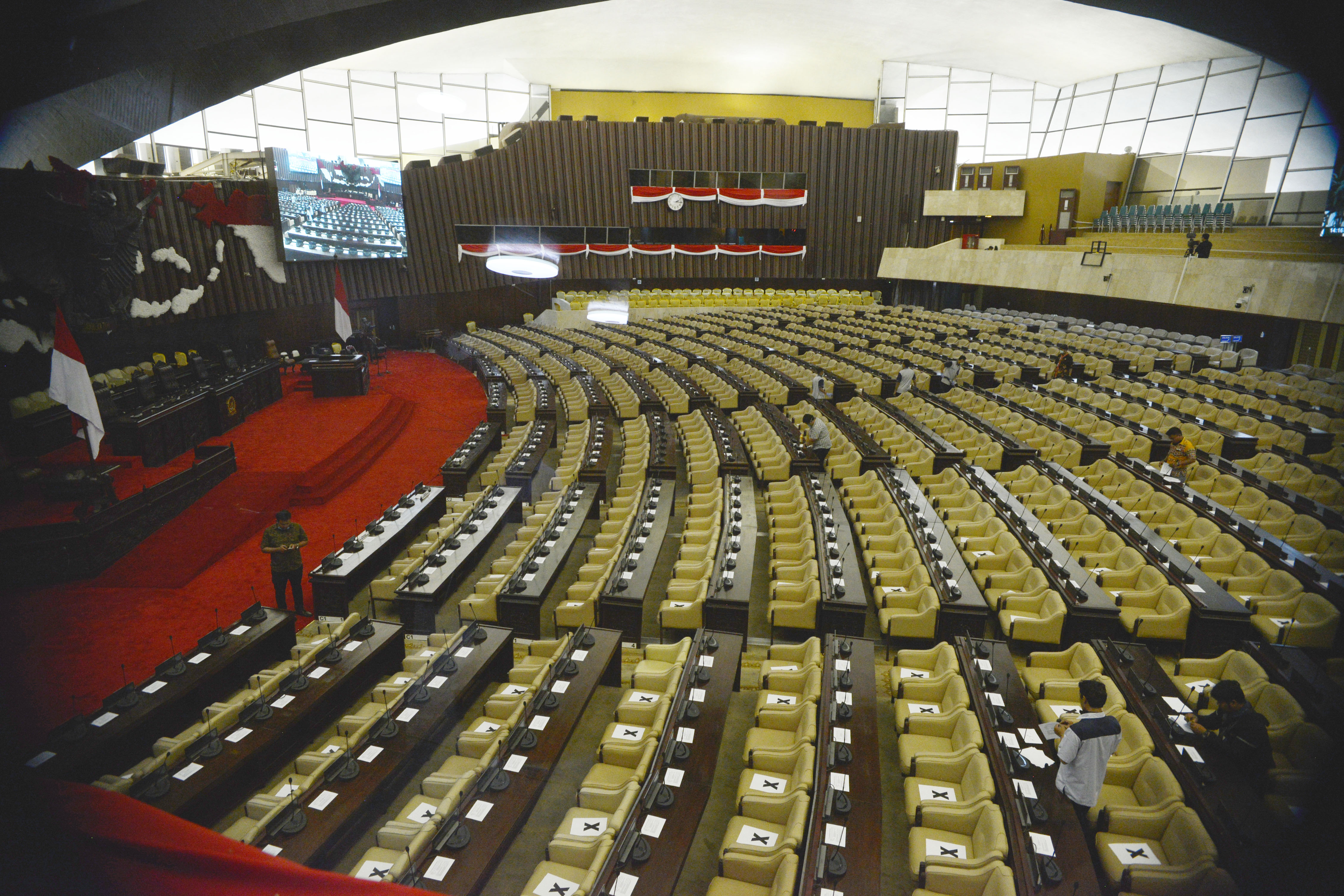 Staf Kesekjenan DPR-RI memasang lembaran tanda silang untuk pengaturan jarak antar anggota Dewan pada persiapan pelaksaan Rapat Paripurna