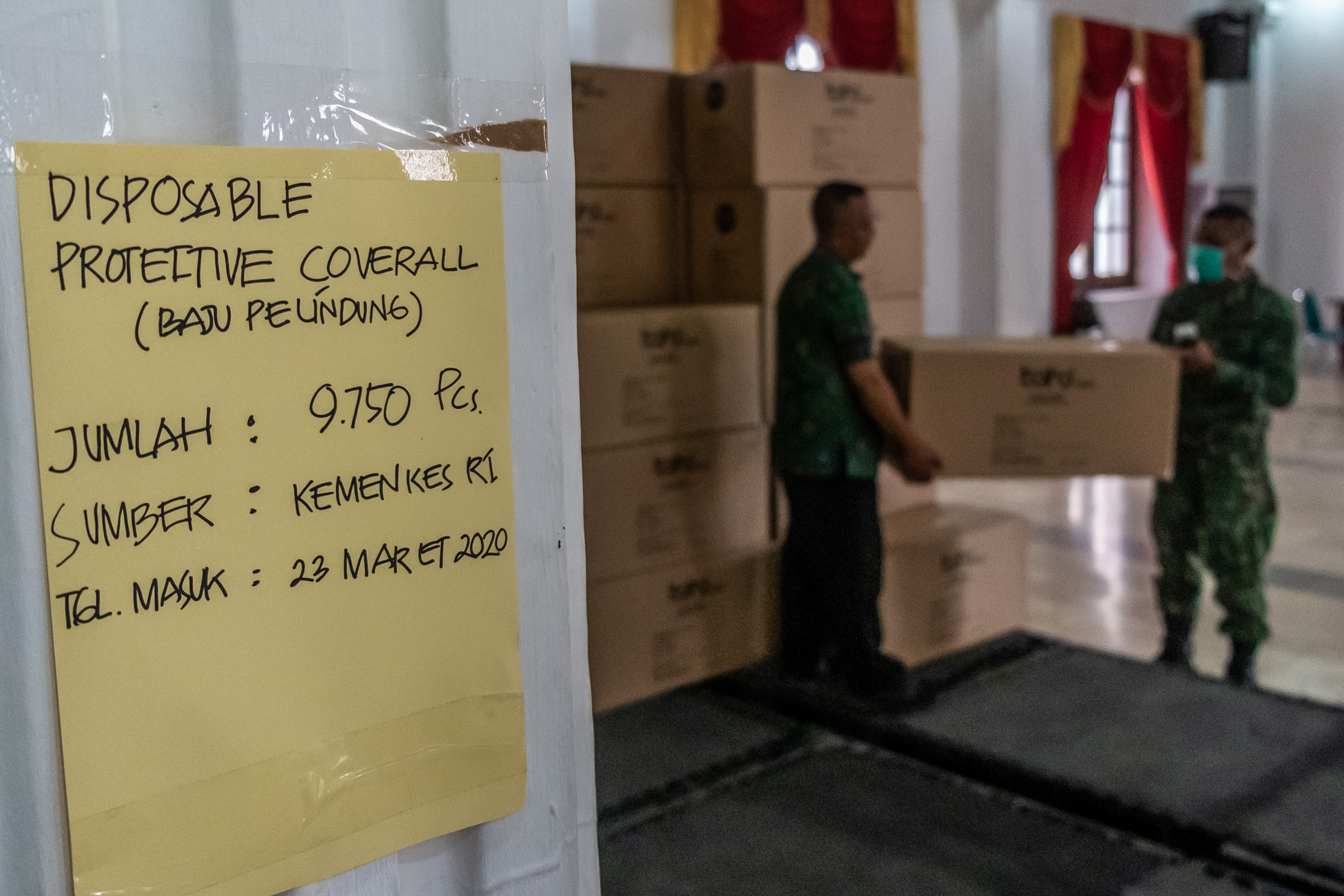 Petugas mengangkat bantuan logistik kesehatan berupa baju pelindung (Disposable Protective Coverall) di Wisma Perdamaian, Semarang, Selasa.