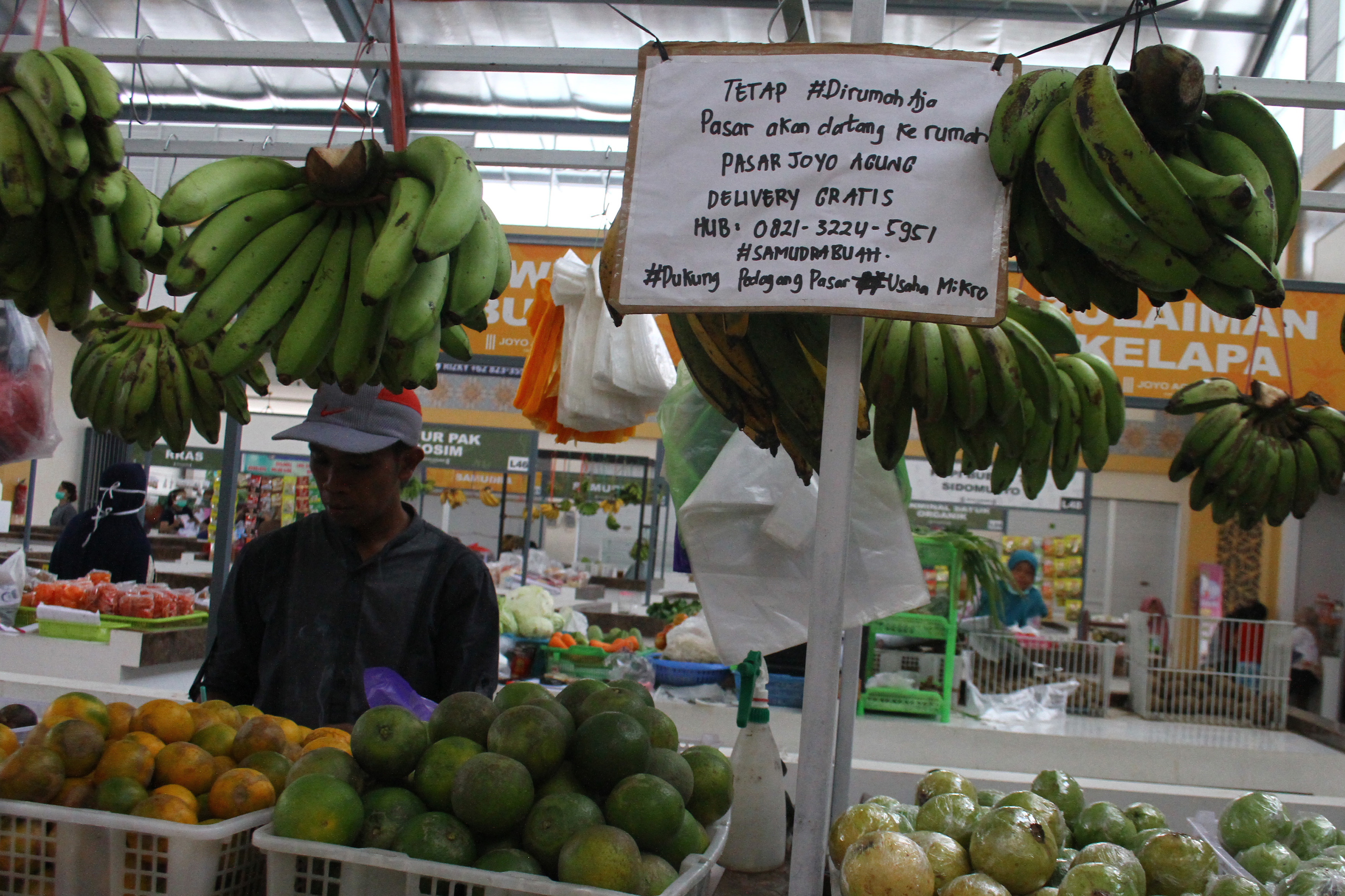 Pedagang menyiapkan sayuran dan buah yang dibeli konsumen melalui aplikasi pesan instan di pasar Joyoaagung, Malang.