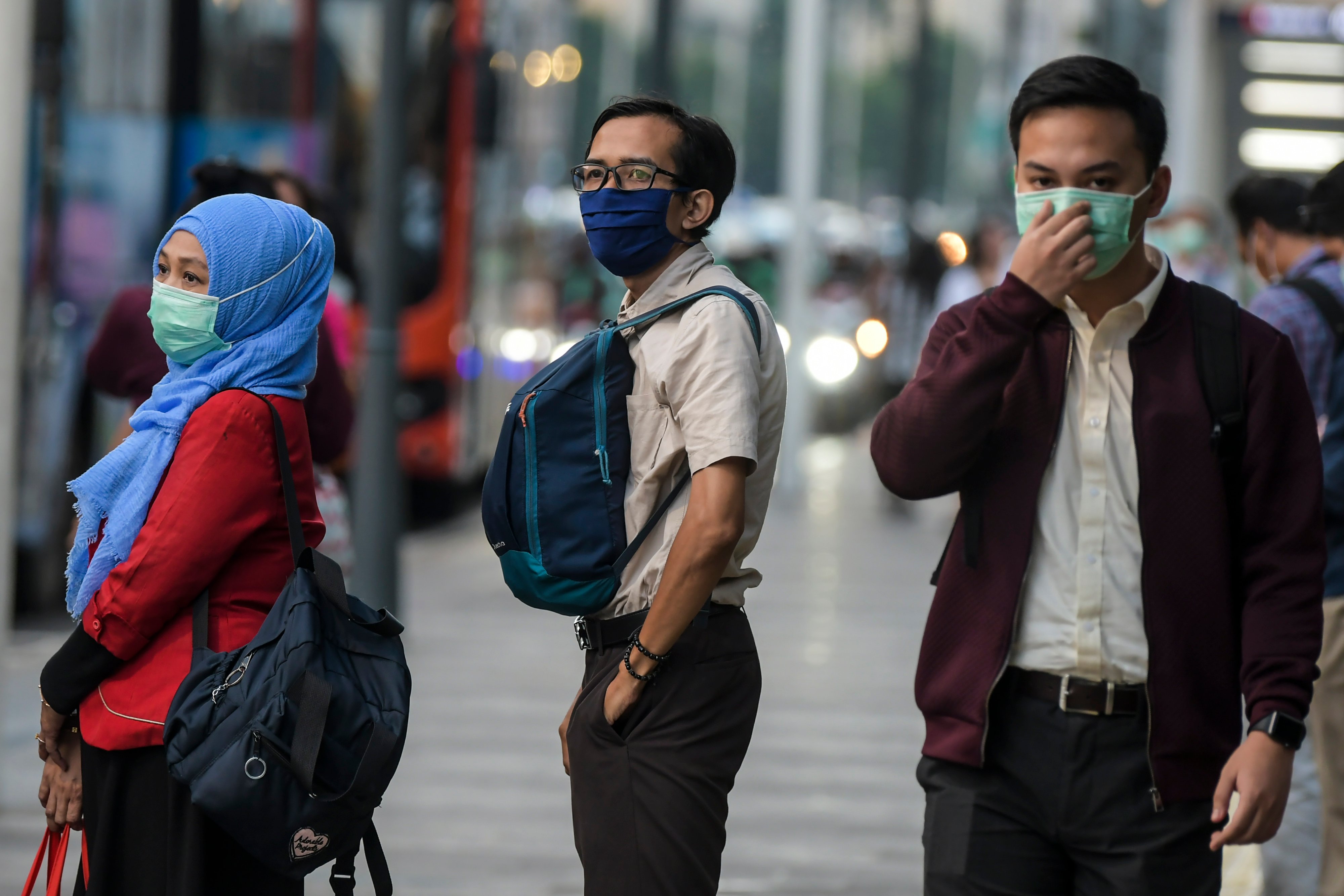 Warga beraktivitas menggunakan masker di kawasan Bunderan Hotel Indonesia, Jakarta, Senin (2/3/2020).