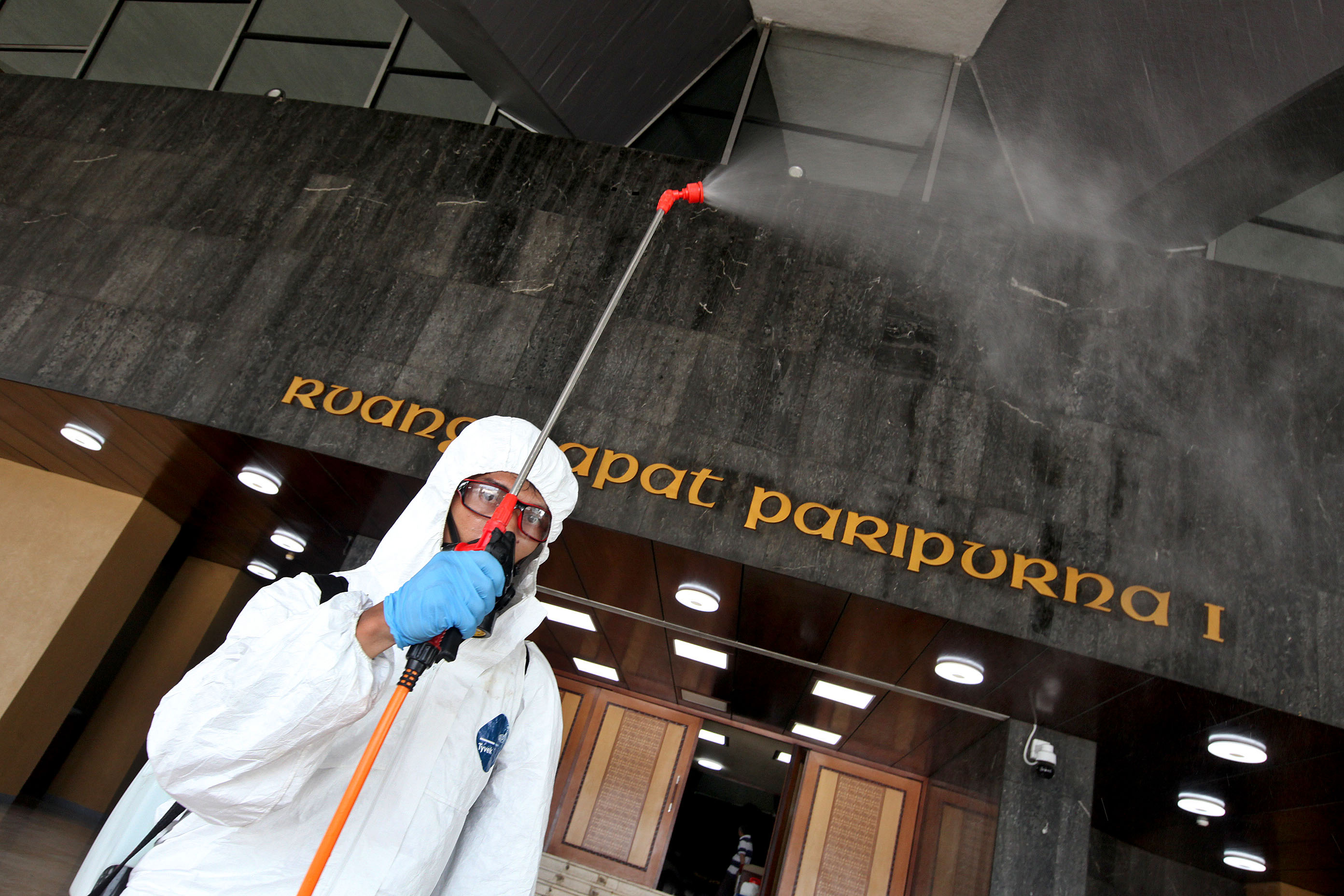 Petugas melakukan penyemprotan disinfektan di area Gedung Paripurna, Nusantara I, Kompleks Parlemen Senayan, Jakarta, Minggu (29/03/2020