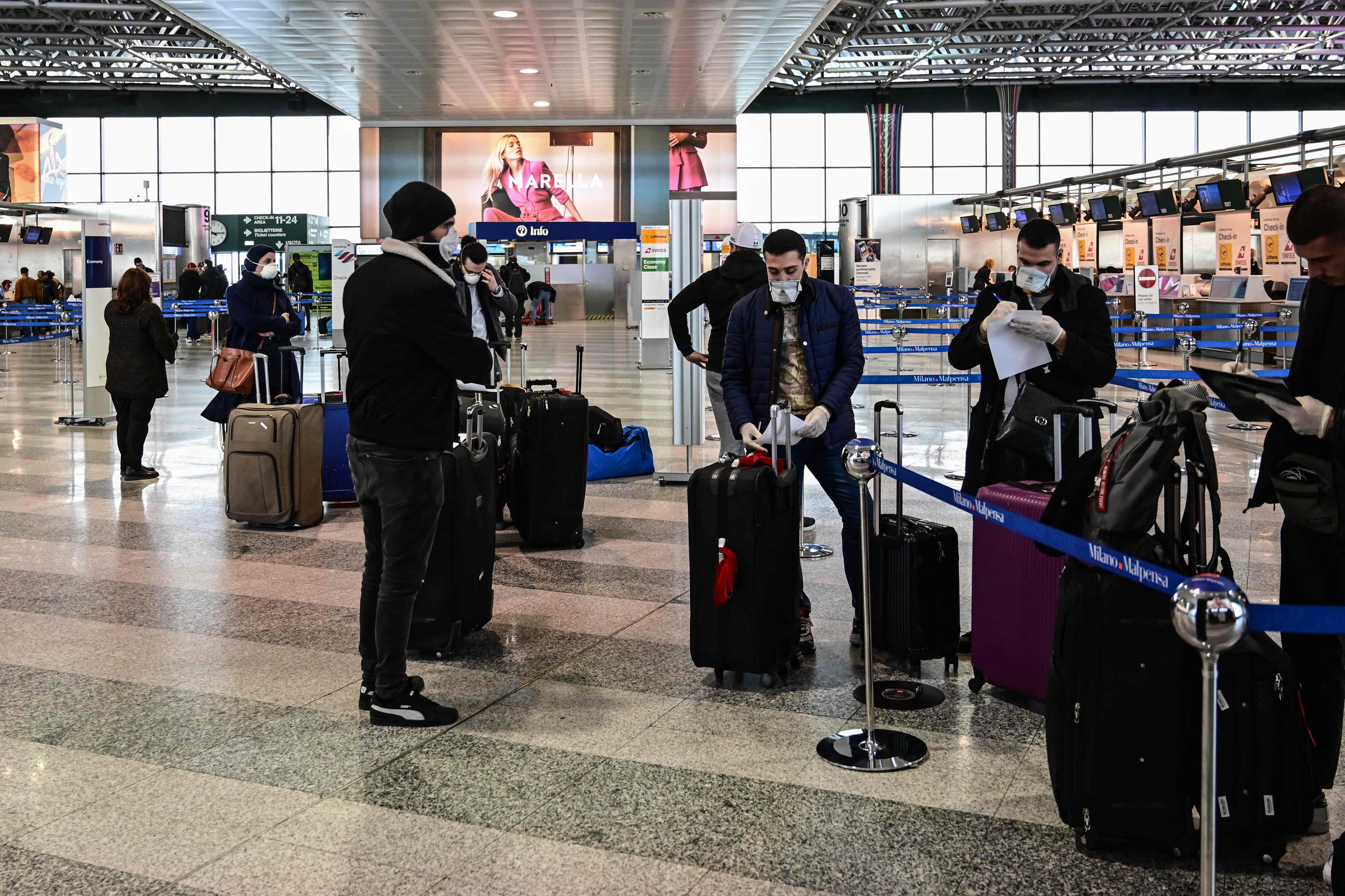 Calon penumpang mengenakan masker menunggu melakukan check in di Bandara Milan-Malpensa, Milan, Italia.