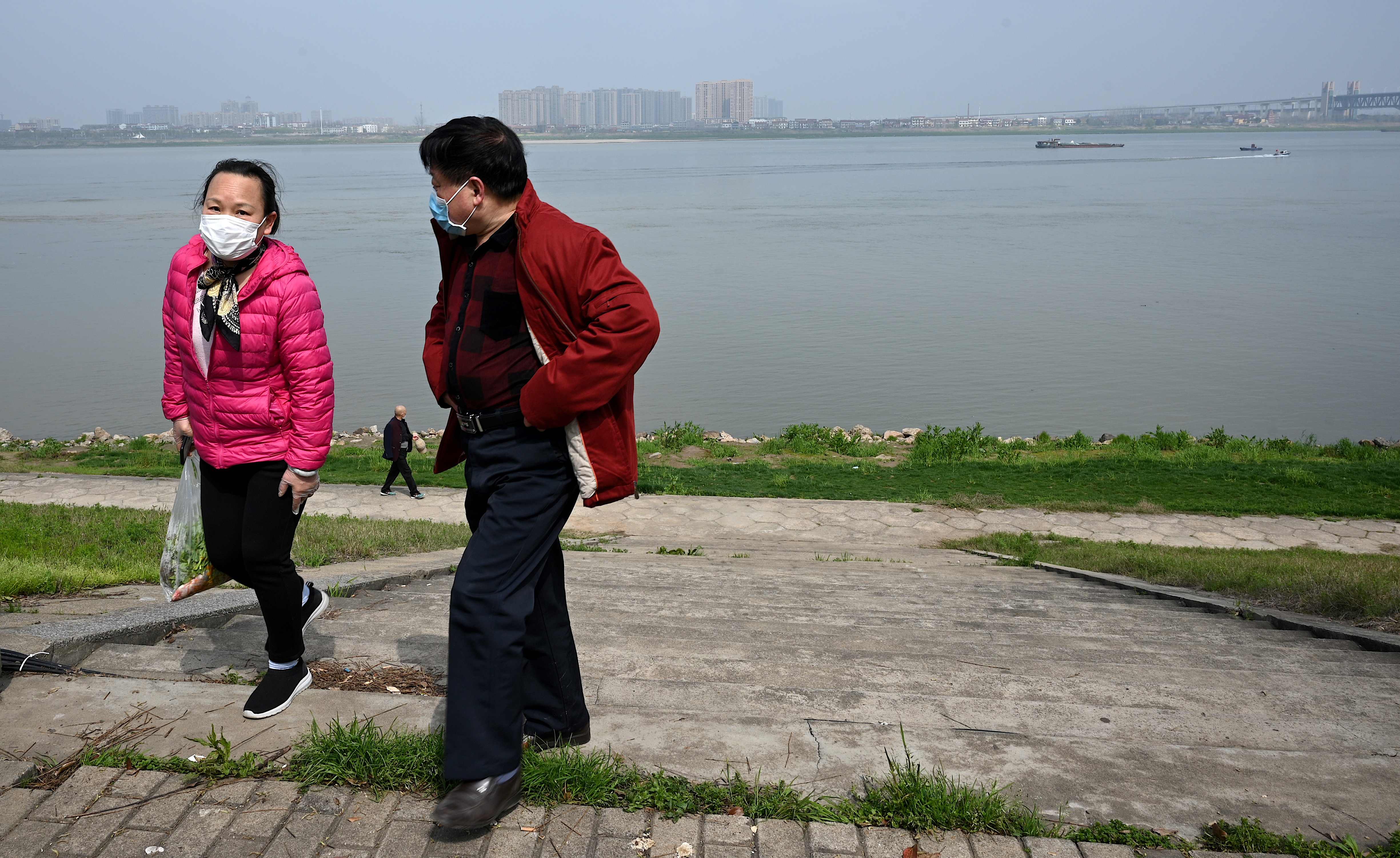 Pasangan menggunakan masker saat santai di sisi sungai Changjiang, Juijiang, Provinsi Jiangxi, Tiongkok, Sabtu (14/3).