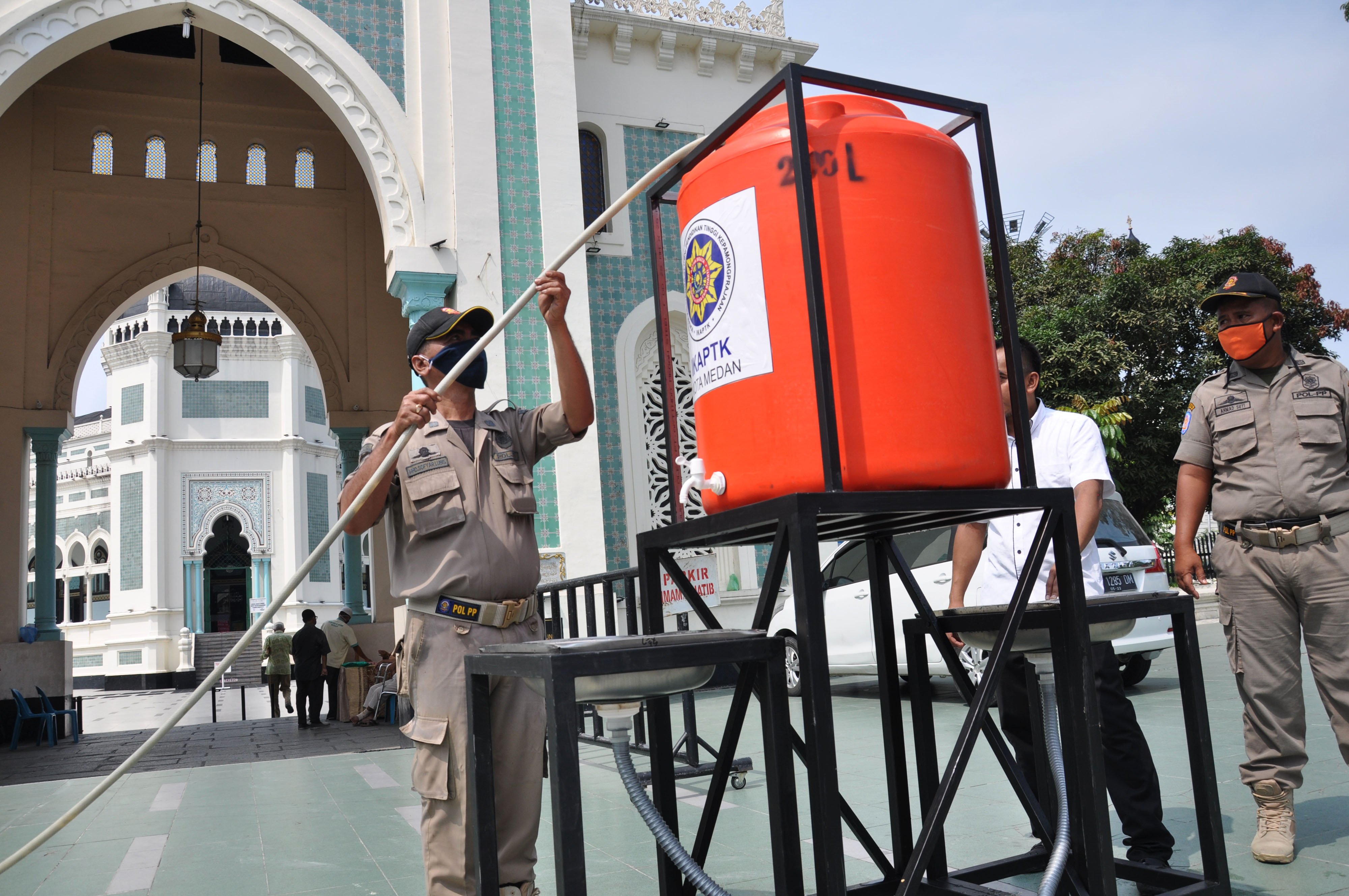 Petugas Satpol PP Pemkot Medan mengisi air tempat mencuci tangan di depan halaman Masjid Raya Al Mashun Medan.