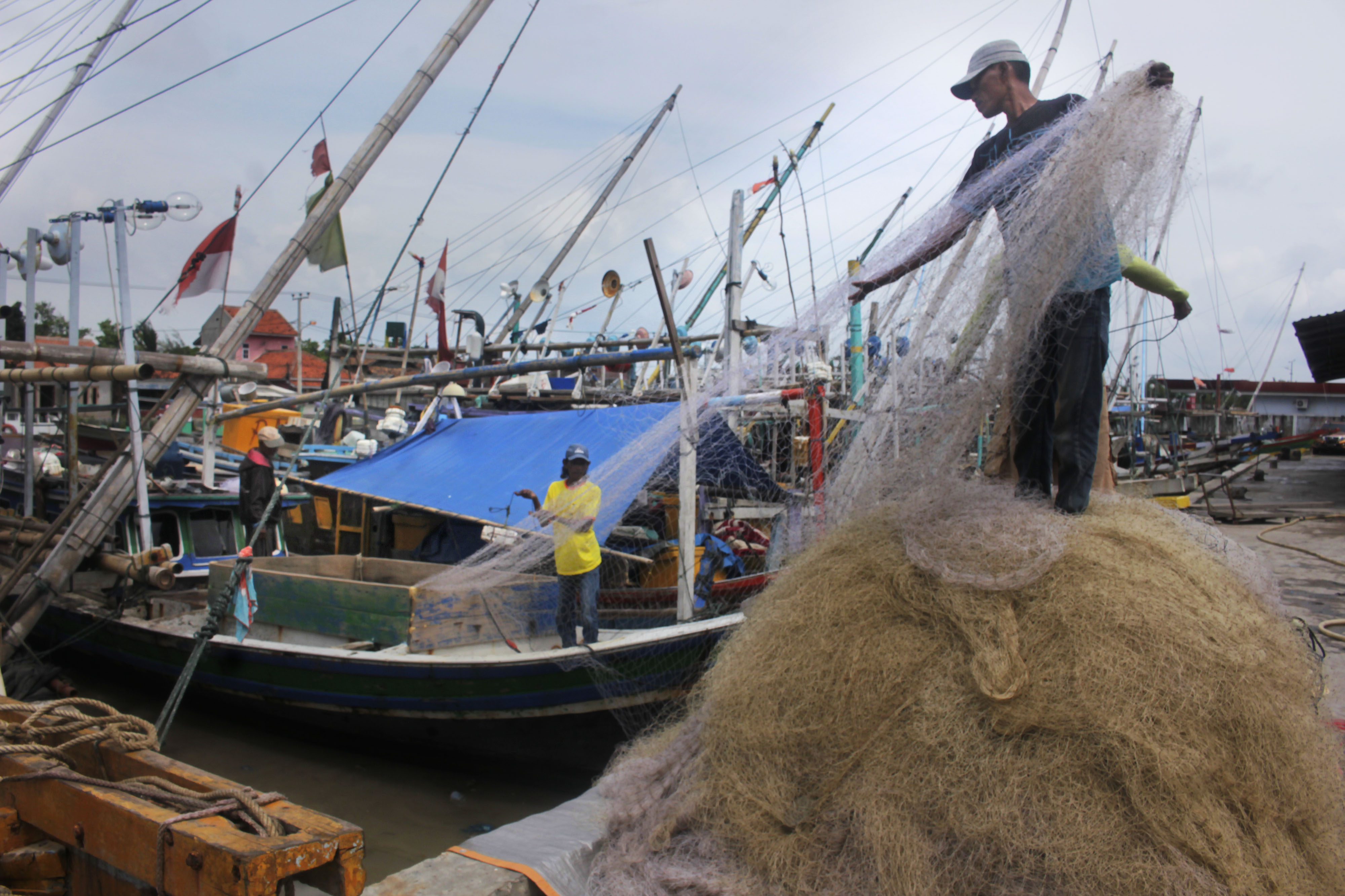 Nelayan tidak bisa melaut karena cuaca ekstrem sehingga mereka mengisi hari dengan memperbaiki jaring
