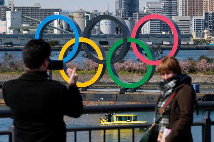 Warga Jepang berpose di logo cincin Olimpiade yang ada di Odaiba Marine Park, Tokyo