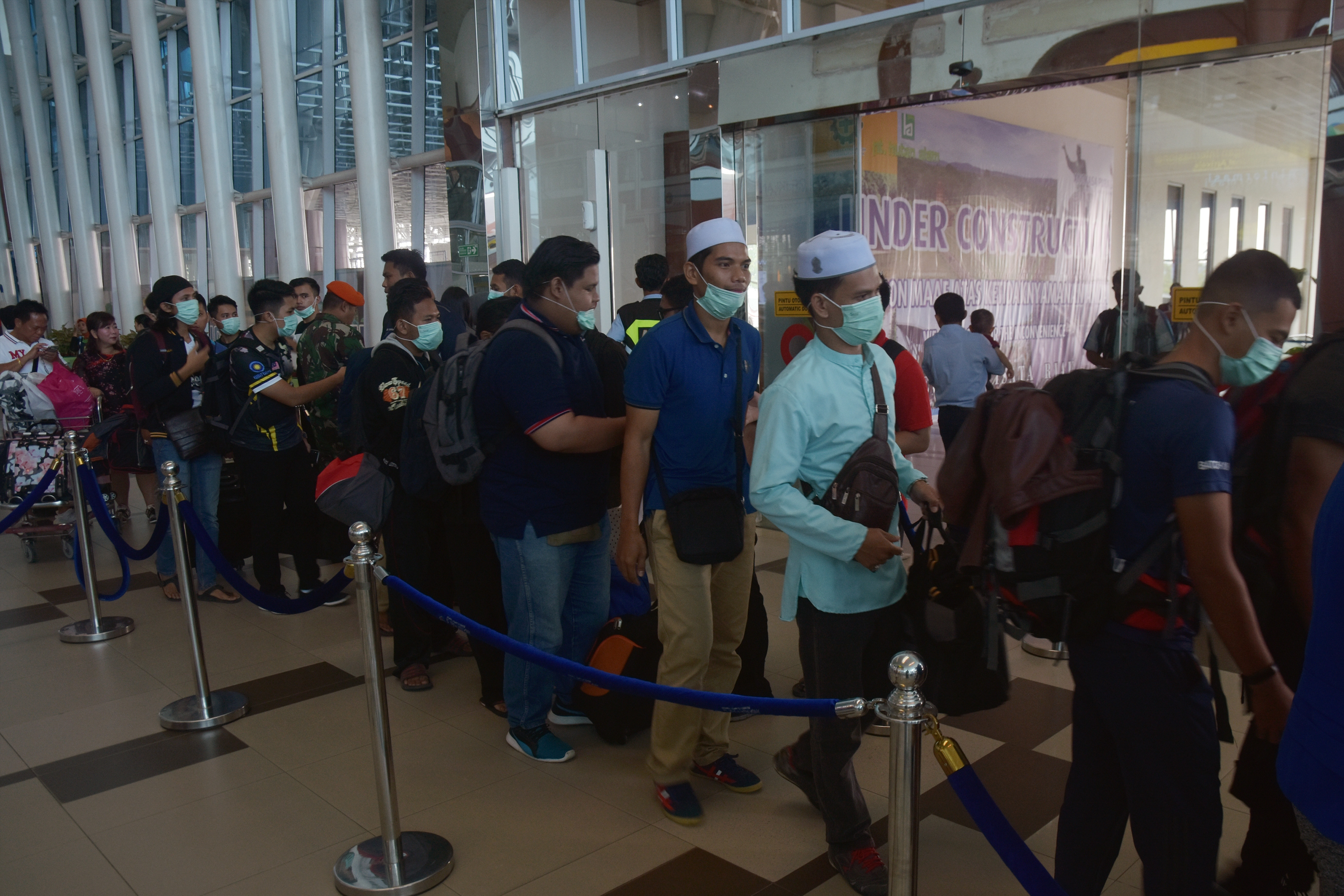 Para penumpang mengenakan masker di Bandara Sultan Syarif Kasim II (SSK II) di Kota Pekanbaru, Provinsi Riau.