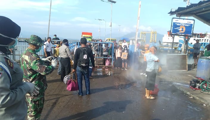 Penumpang yang baru turun di Pelabuhan Larantuka disemprot disinfektan.