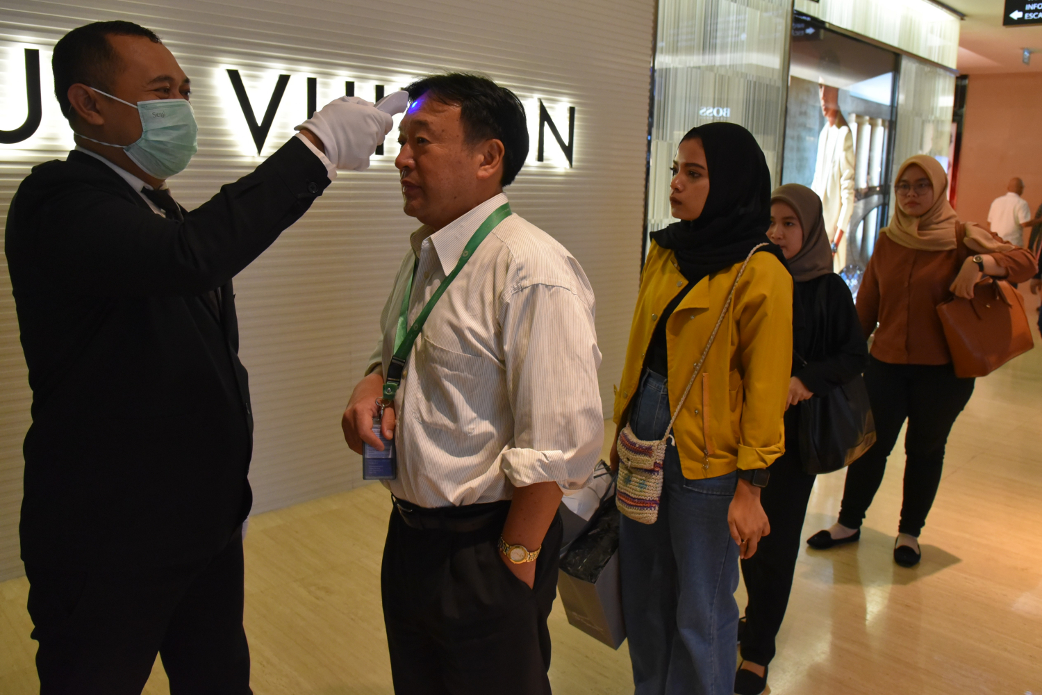 Petugas memeriksa suhu tubuh pengunjung Plaza Indonesia di Jakarta Pusat, Kamis (5/3).