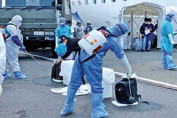 Petugas kesehatan menyemprotkan cairan disinfektan ke WNI kru kapal Diamond Princess saat turun dari kapal di Yokohama, Jepang, kemarin.
