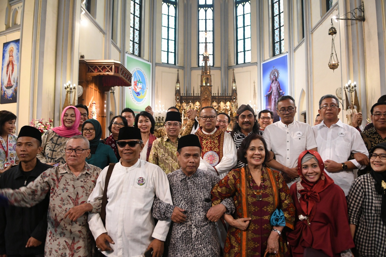 Sejumlah anggota komunitas lintas agama bergandengan tangan saat foto bersama di sela misa Natal di Gereja Katedral Jakarta.