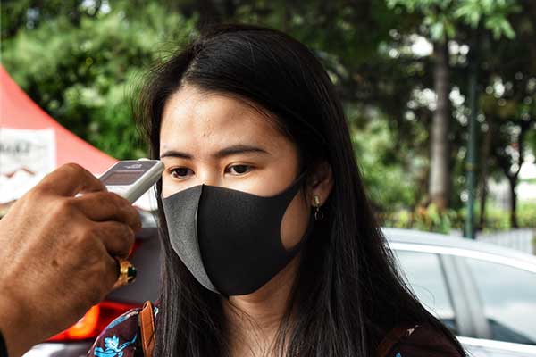 Ilustrasi -- Polisi cek suhu tubuh pengunjung di pintu masuk kantor SPKT dan Samsat Polda Metro Jaya, Jakarta Selatan (12/3/2020)