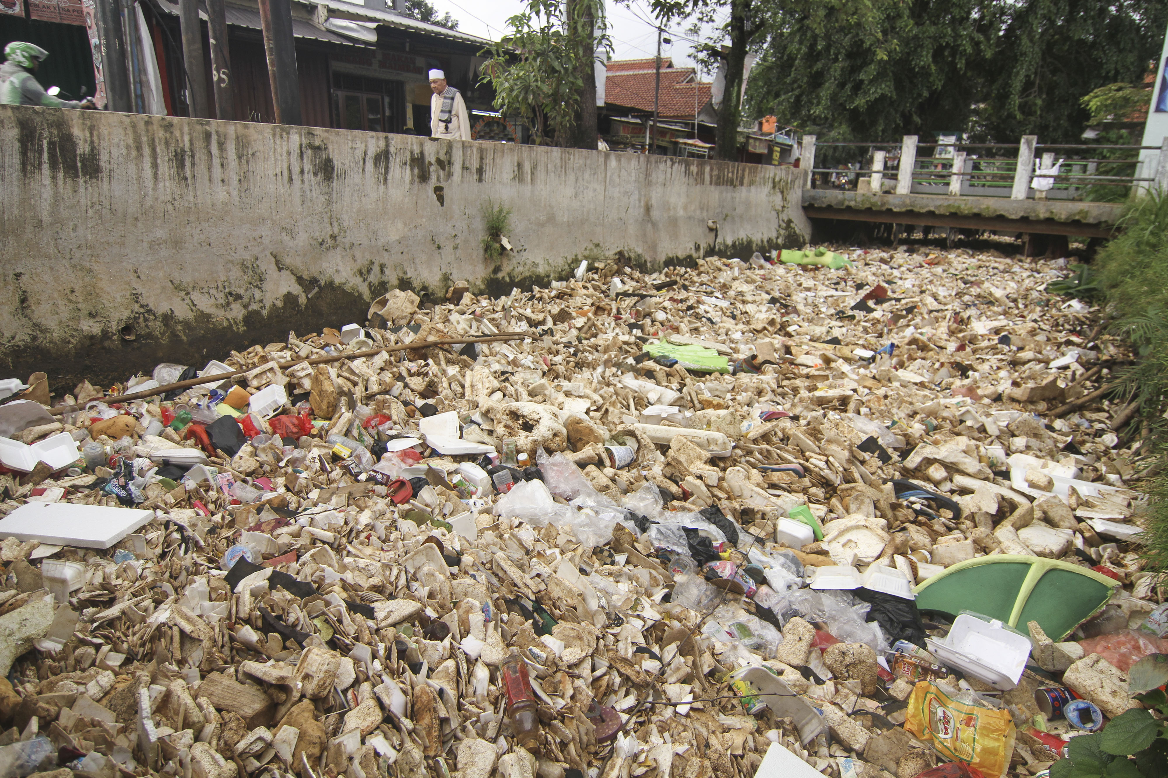 Warga melintas di samping kali Licin yang dipenuhi sampah di Depok, Jawa Barat, Jumat (28/2).