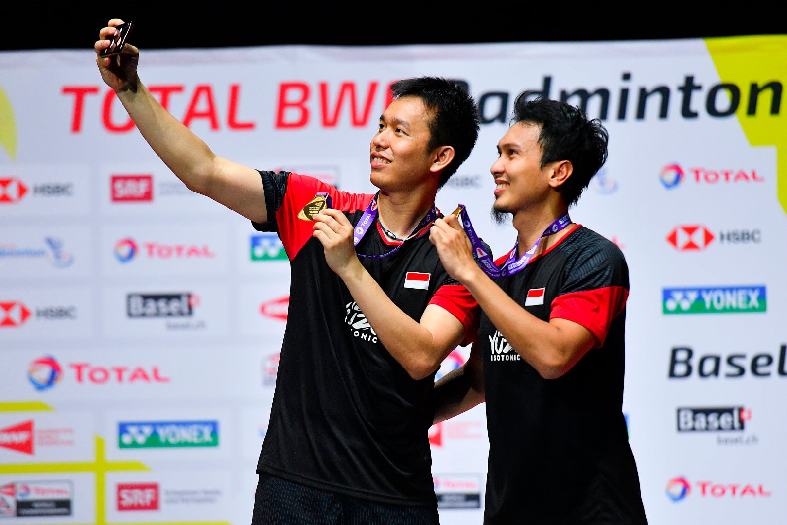 Ganda putra Indonesia, Hendra Setiawan dan Mohammad Ahsan, berswafoto dengan medali emas di Kejuaraan Dunia Bulu Tangkis 2019.