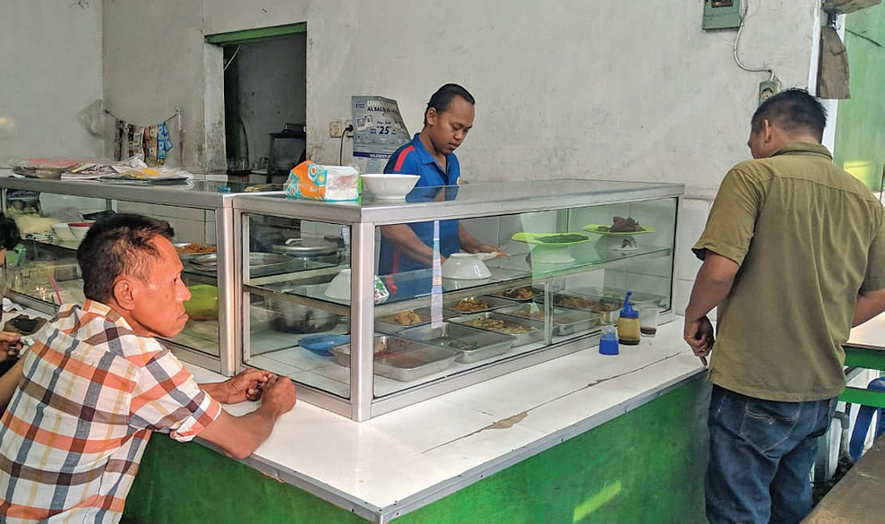 MAKAN SIANG GRATIS: Pelayan menyiapkan menu makan siang di Warung Tegal (Warteg) Putra Bahari di Jatinegara Barat
