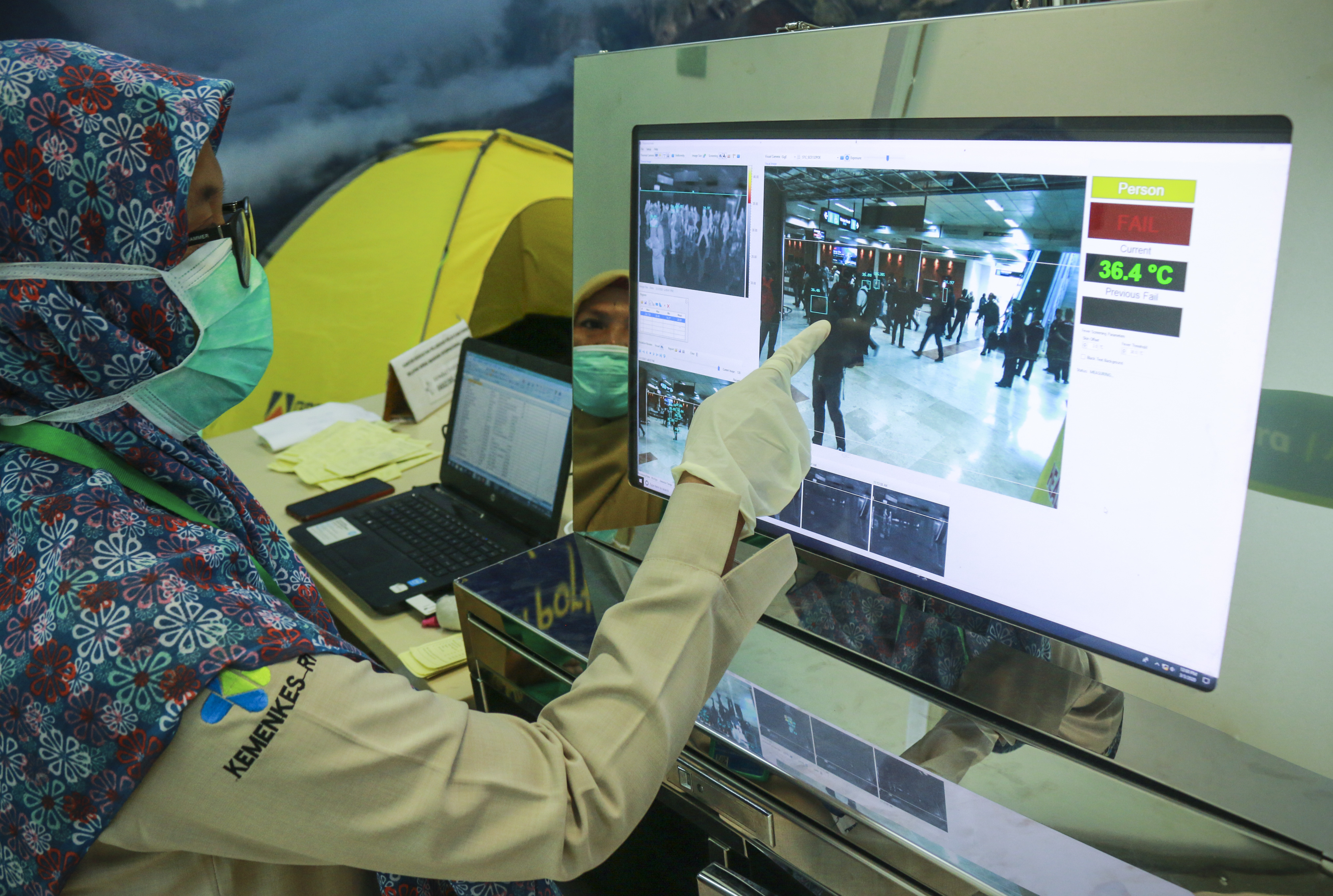  Petugas mengamati penumpang pesawatÊyang baru tiba melalui thermal scanner di terminal kedatangan Bandara Internasional Lombok, NTB.