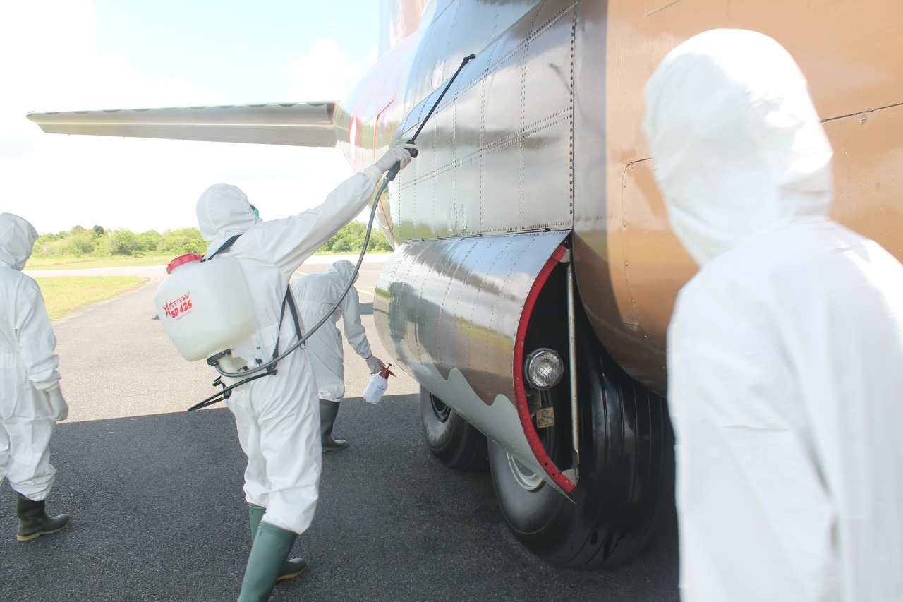 Petugas menyiramkan cairan disinfektan ke pesawat hercules yang membawa logistik medis dari Tiongkok.