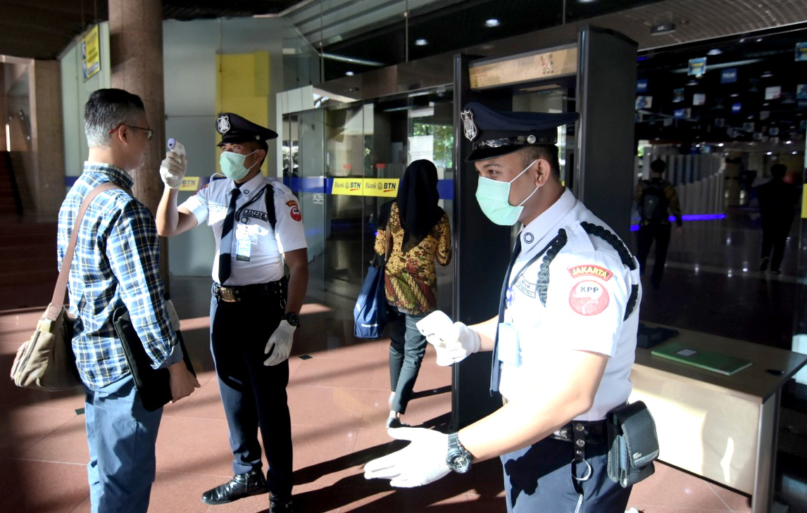 Petugas keamanan PT Bank Tabungan Negara (Persero) Tbk mengukur suhu karyawan dan pengunjung di Jakarta, Rabu (11/3).