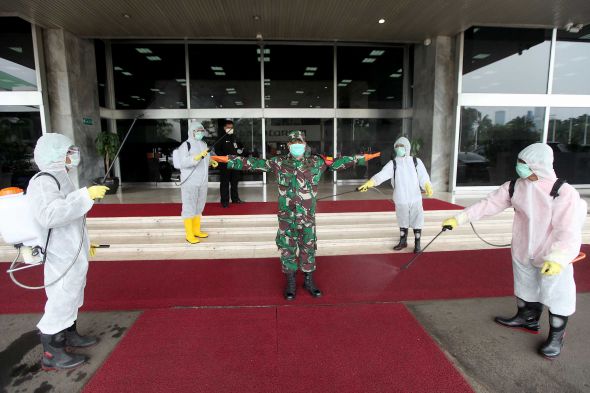 Petugas melakukan penyemprotan cairan disinfektan kepada setiap pengunjung yang datang di depan lobby gedung Nusantara III DPR.