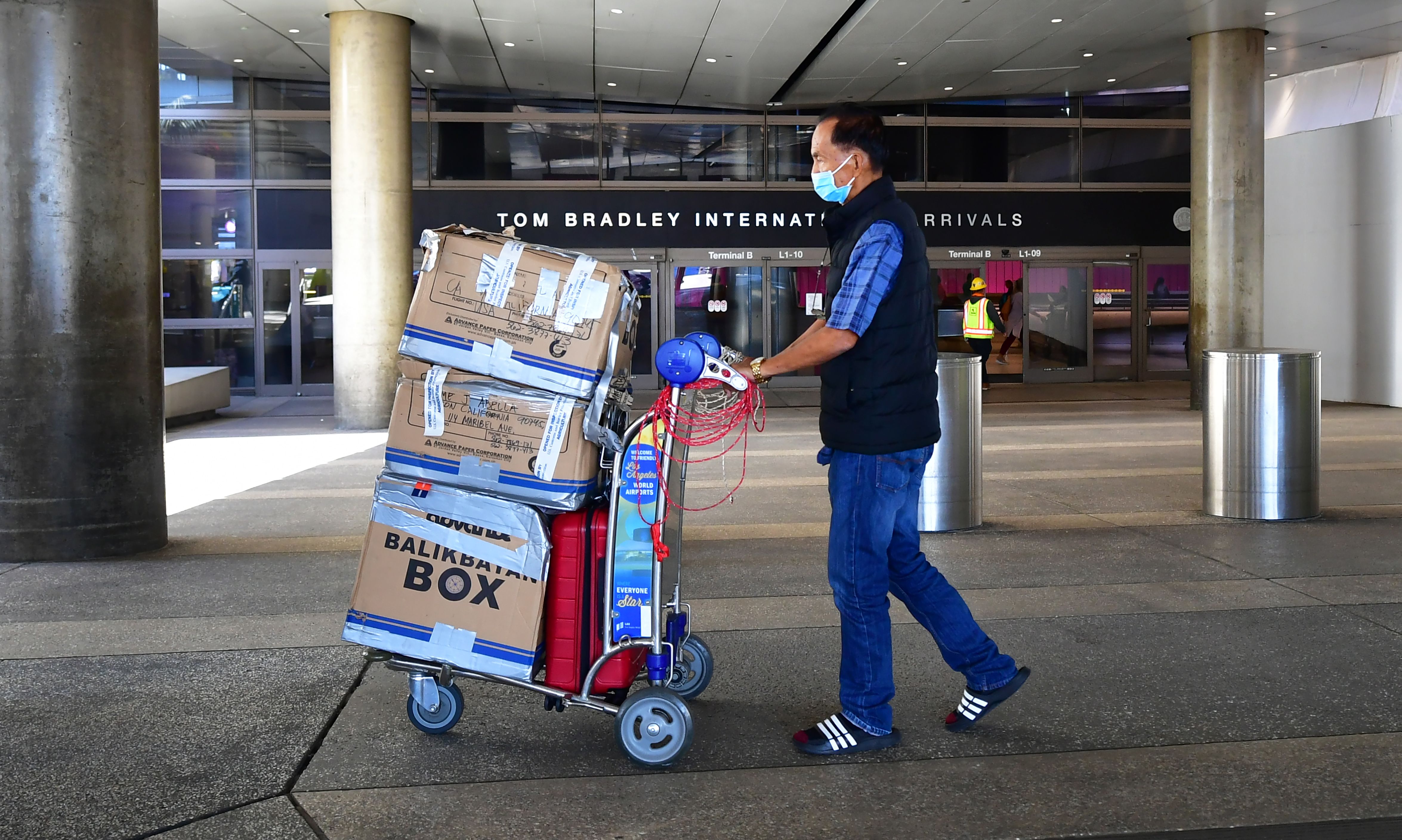 Seorang pria mengenakan masker saat berada di Bandara Los Angeles, California, Amerika Serikat.