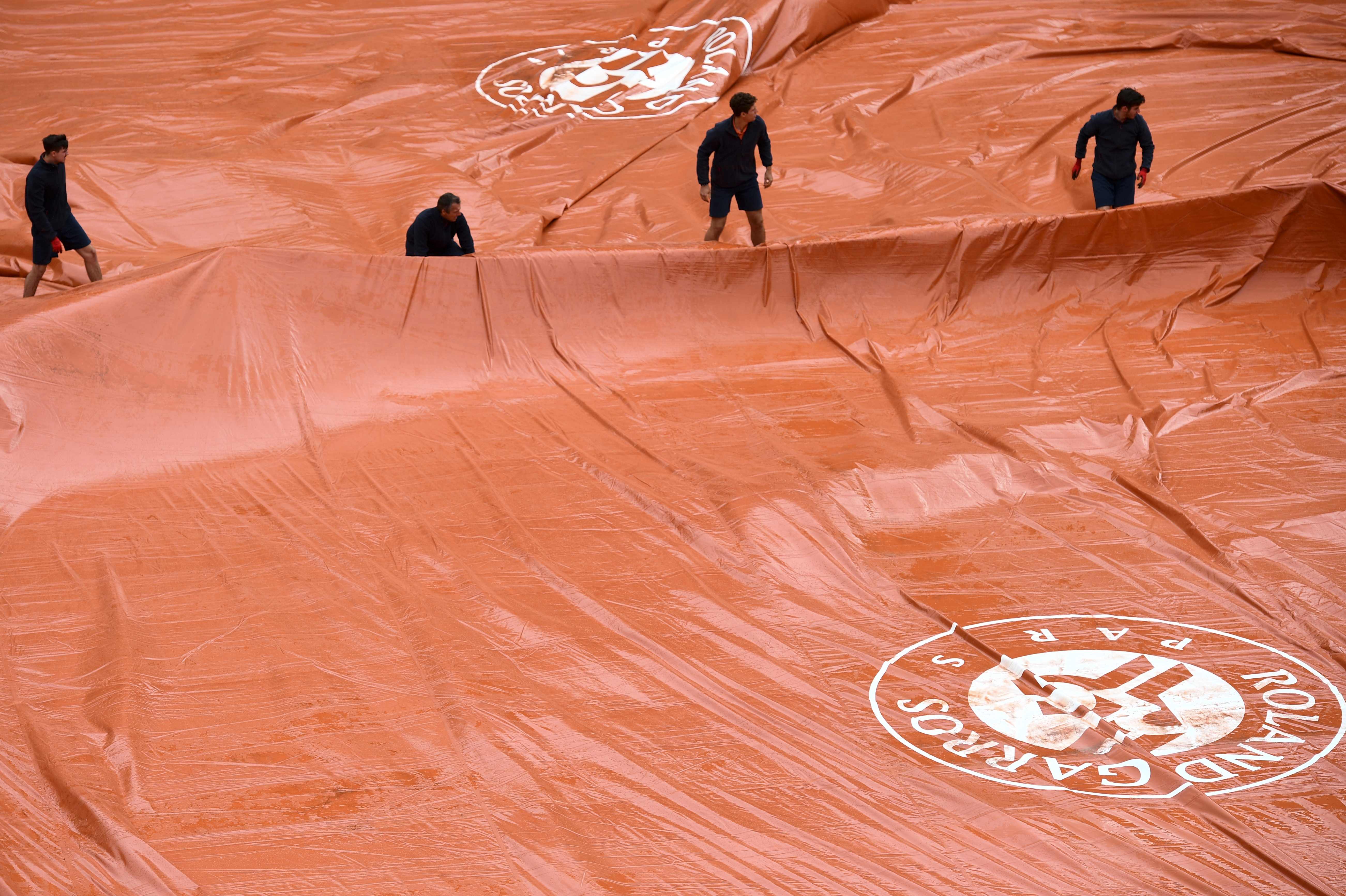 Petugas menarik penutup lapangan saat hujan terjadi di ajang Prancis Terbuka.