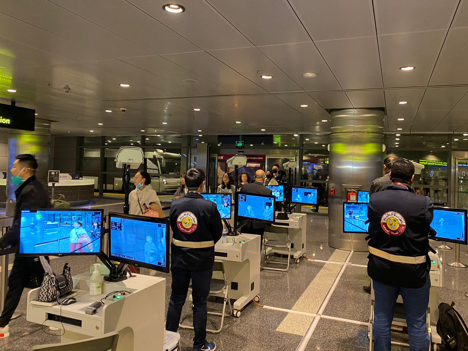 Pelancong berjalan melalui alat pemindai suhu tubuh di bandara Doha, Qatar.