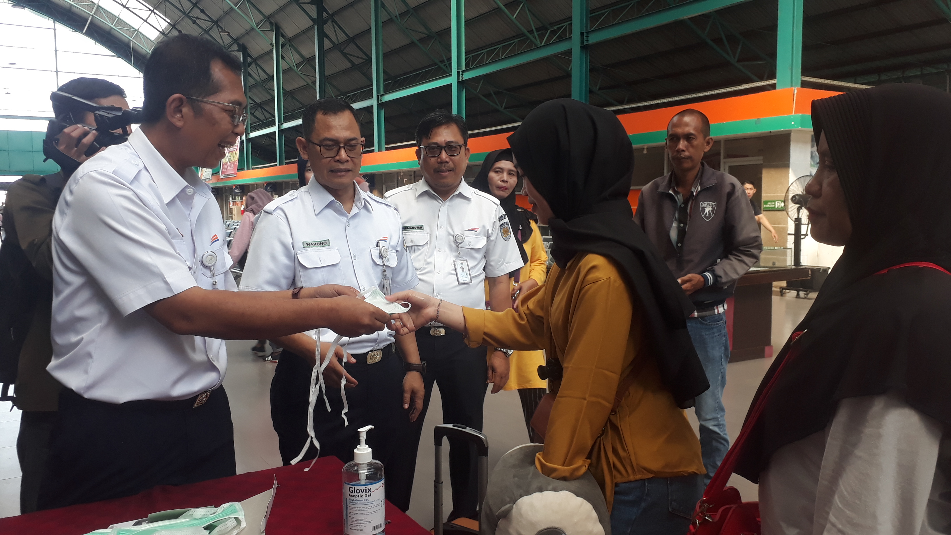 Petugas kereta api di pintu keberangkatan Stasiun Kertapati Palembang membagikan masker dan meminta penumpang cuci tangan. 