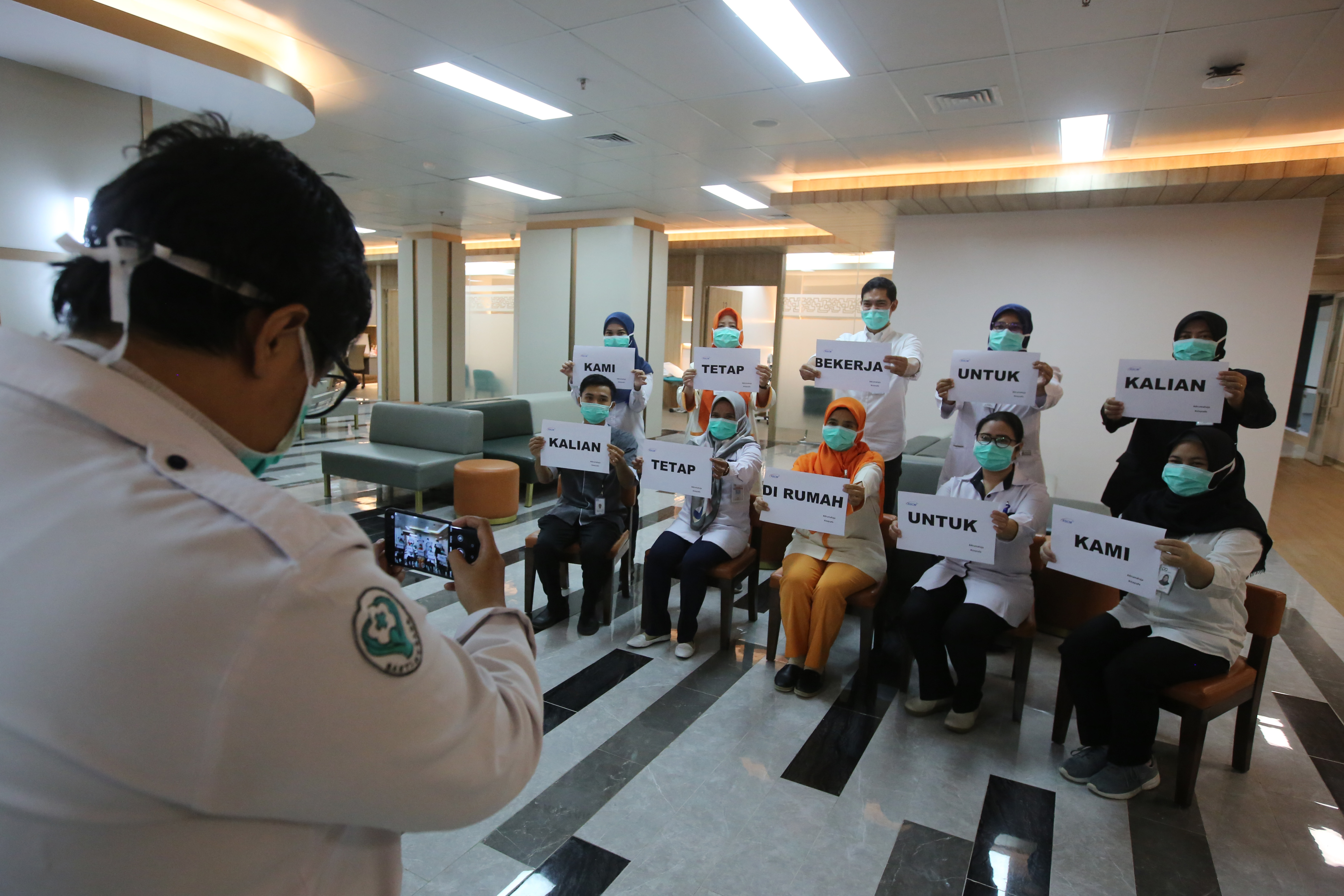 Petugas medis berfoto dengan memegang tulisan 