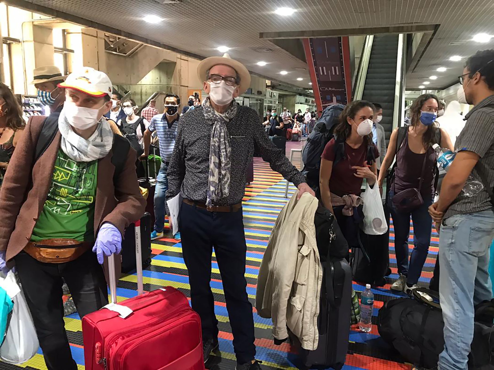 Warga asing mengenakan masker berada di bandara Caracas menunggu pesawat yang akan membawa mereka meninggalkan Venezuela