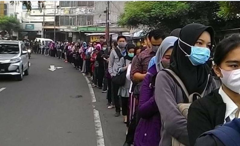Antrean penumpang Trans-Jakarta di Halte Puri Beta setelah diterapkannya pembatasan penumpang oleh Pemprov DKI, Senin (16/3).