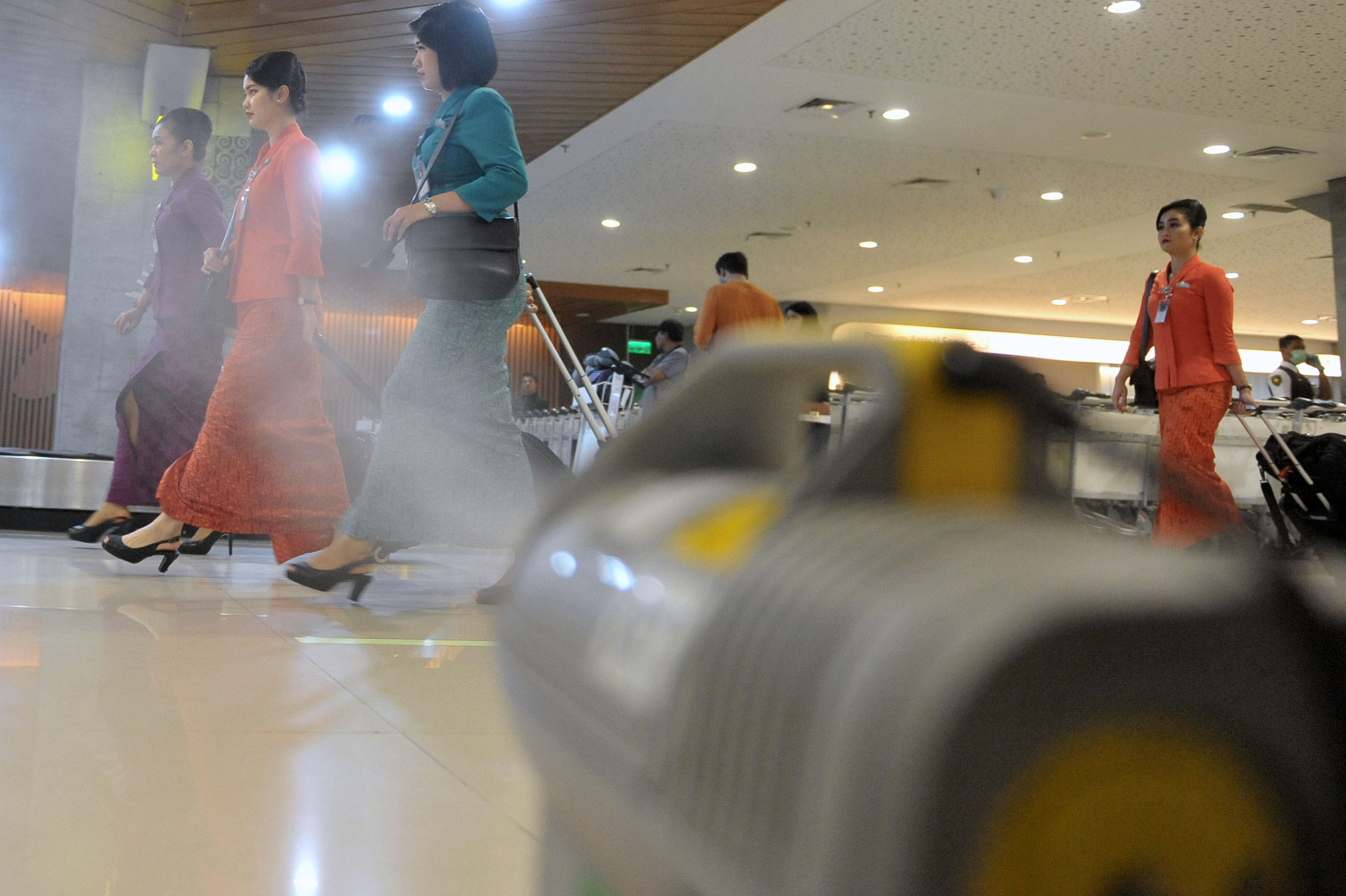 Awak kabin berjalan di dekat alat penyemprot cairan disinfektan otomatis yang dipasang petugas Kantor Kesehatan Pelabuhan Denpasar