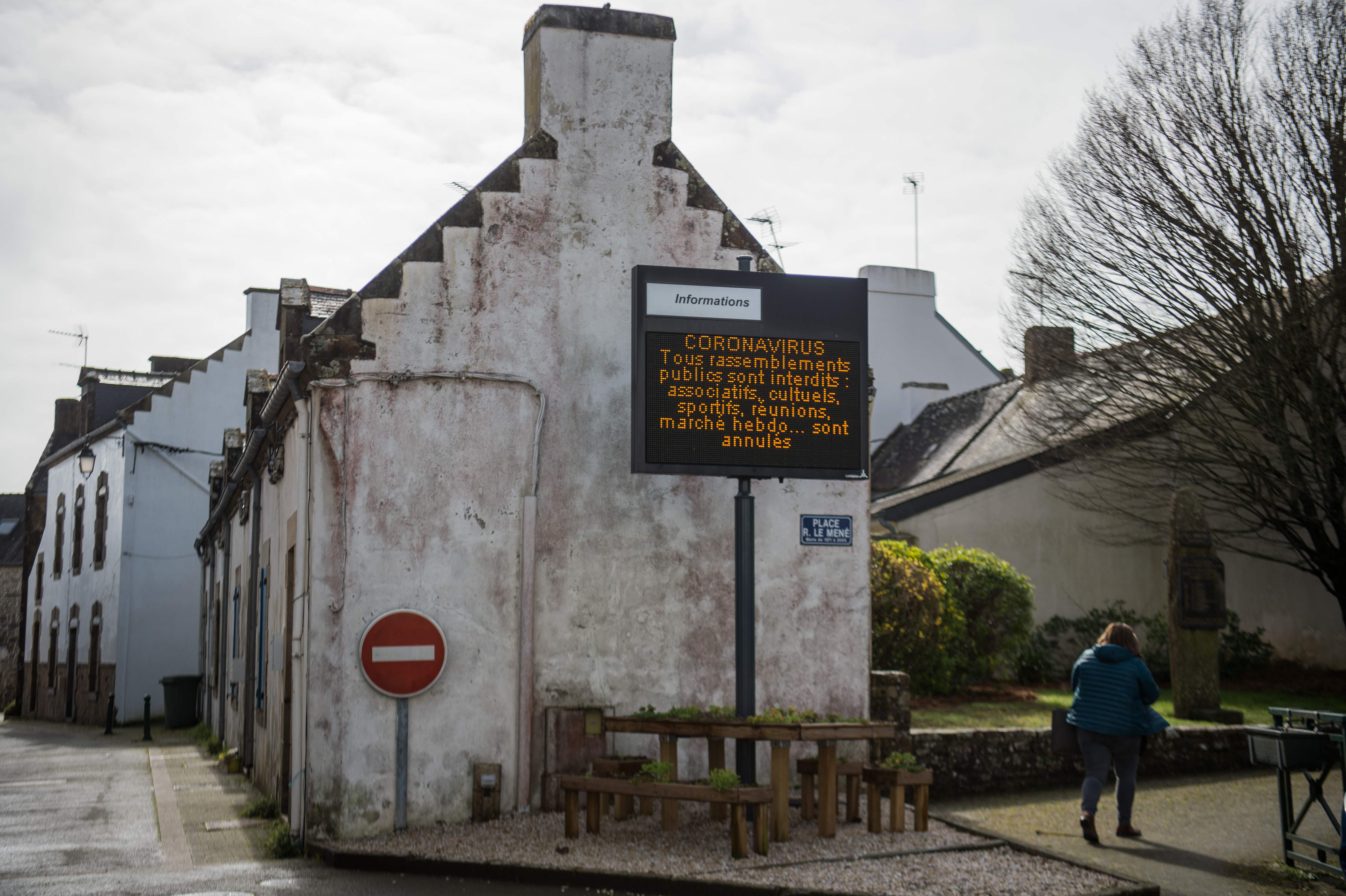 Seorang warga berjalan di depan papan pengumuman berisi larangan berkumpul akibat wabah virus korona di Prancis.