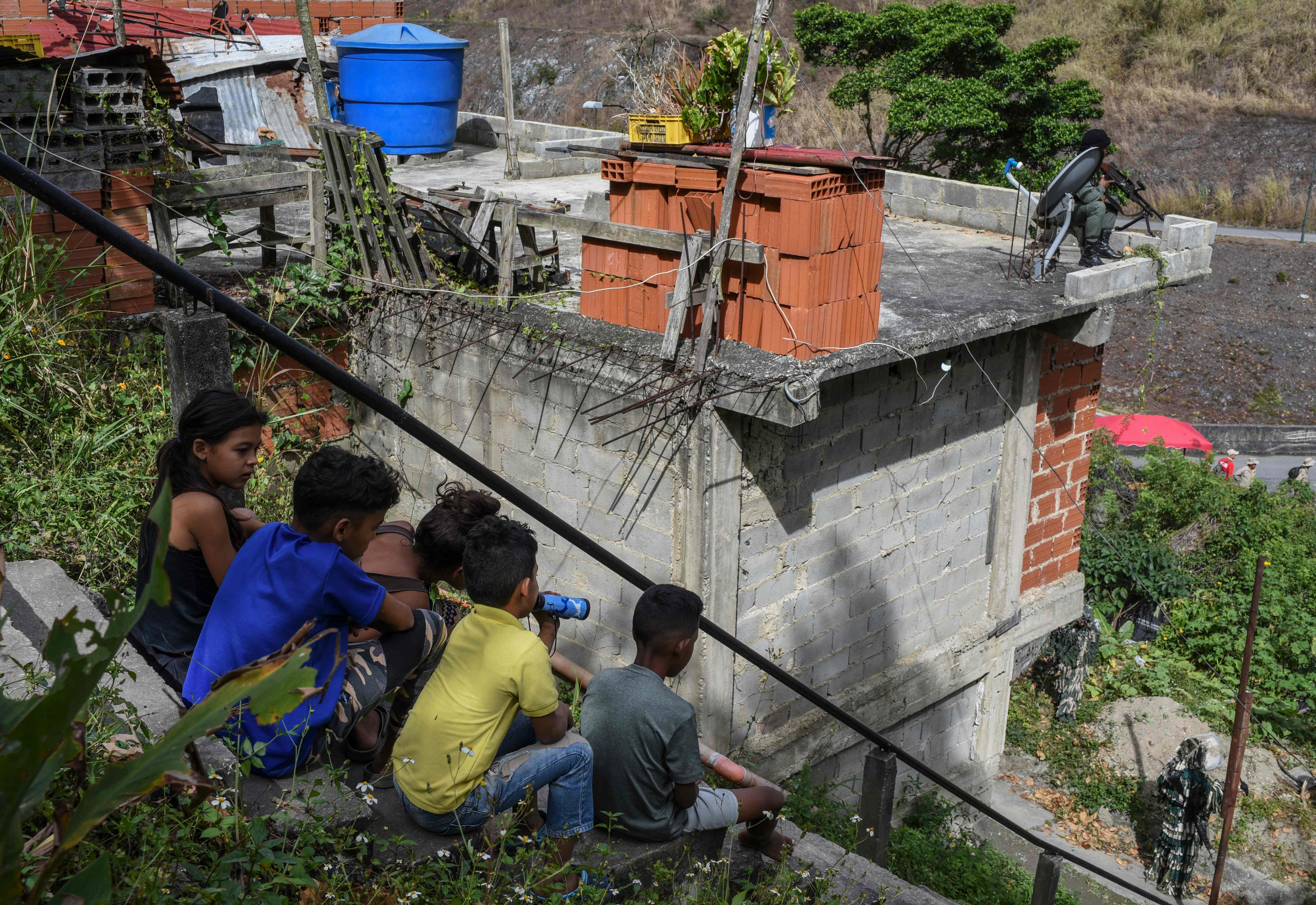Anak-anak menyaksikan militer Venezuela berpatroli di Caracas setelah Maduro menuding AS, Brasil, dan Kolombia akan melancarkan serangan.